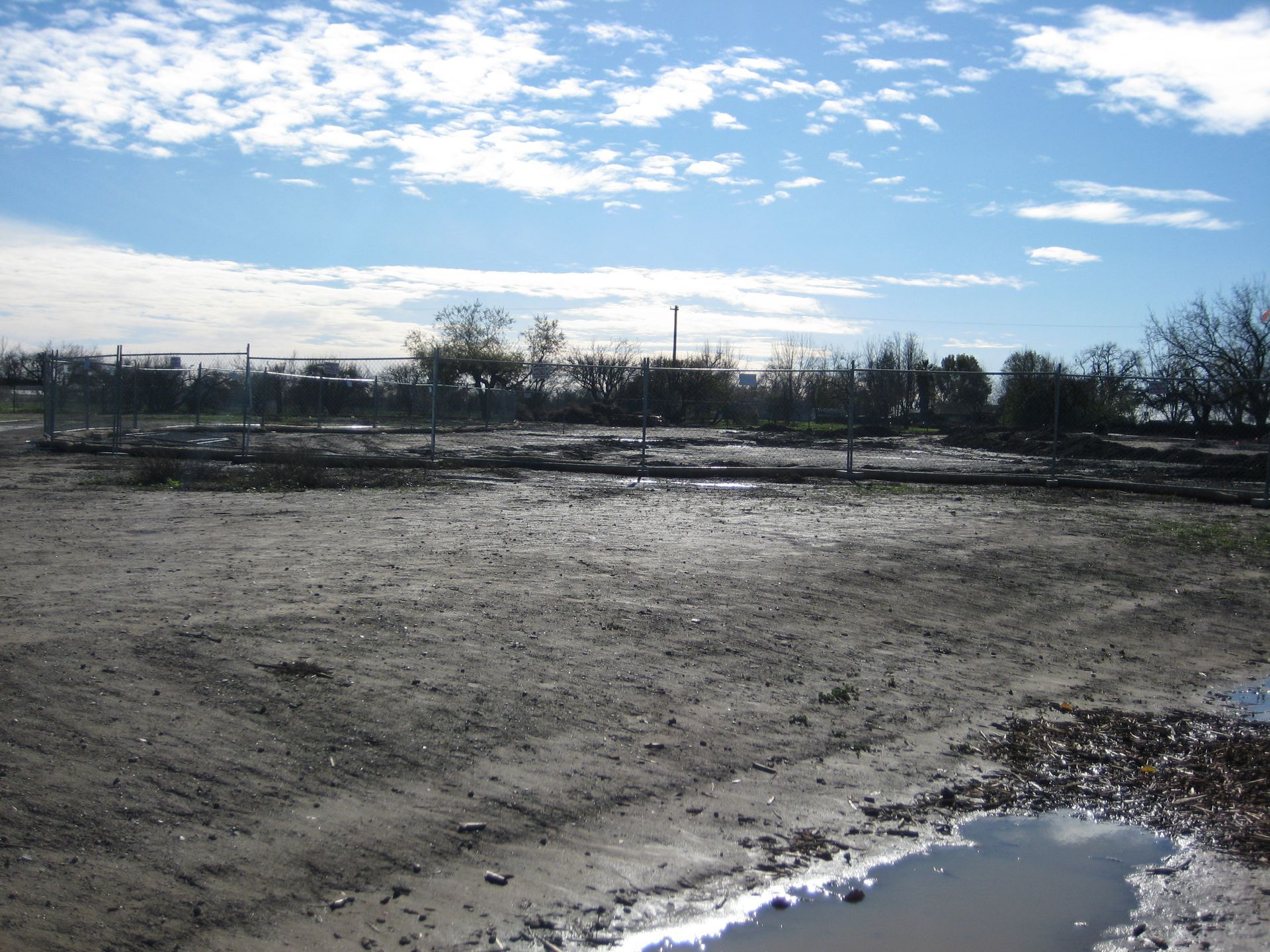 a muddy field with a puddle in the middle