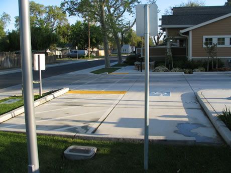 a parking lot with a handicap sign on the sidewalk