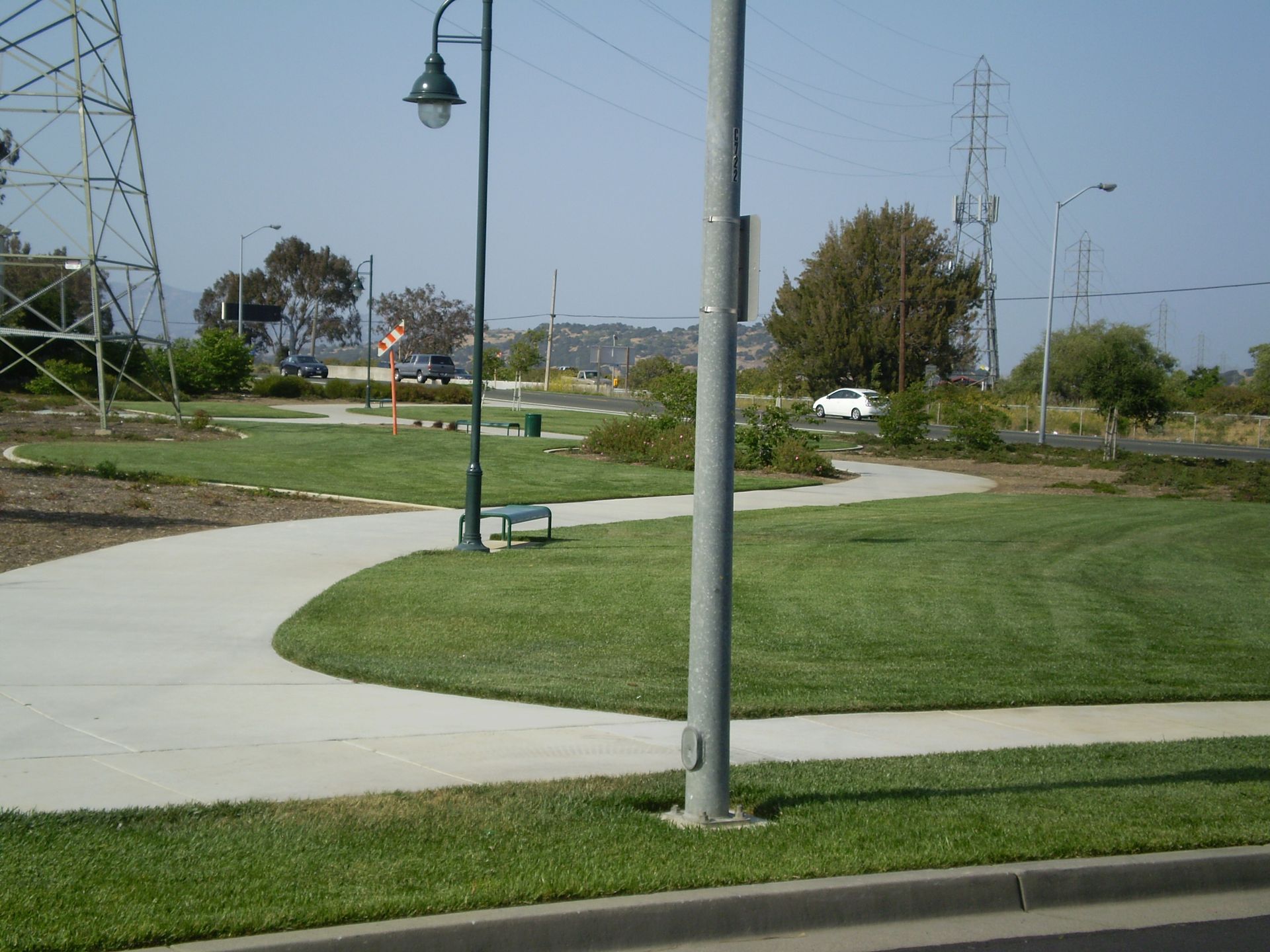 a concrete walkway is surrounded by grass and a street light
