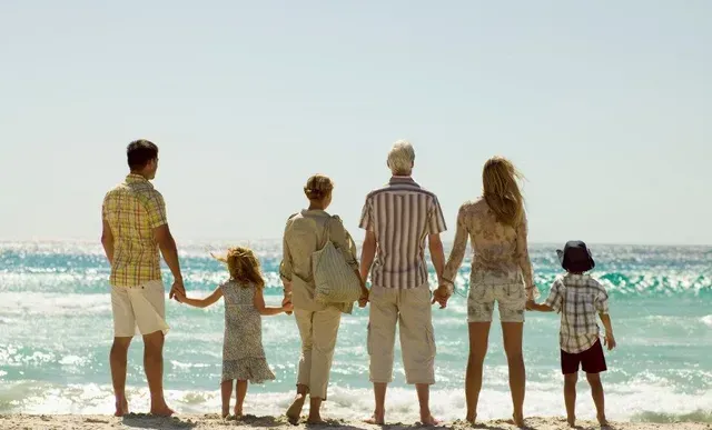 A family stands on the beach hand-in-hand
