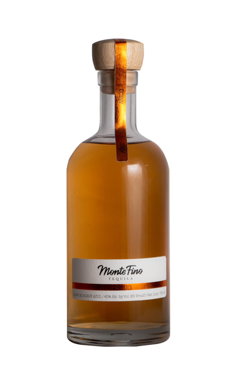 Bottle of Monte Fino tequila with a wooden top and gold label, filled with amber liquid.