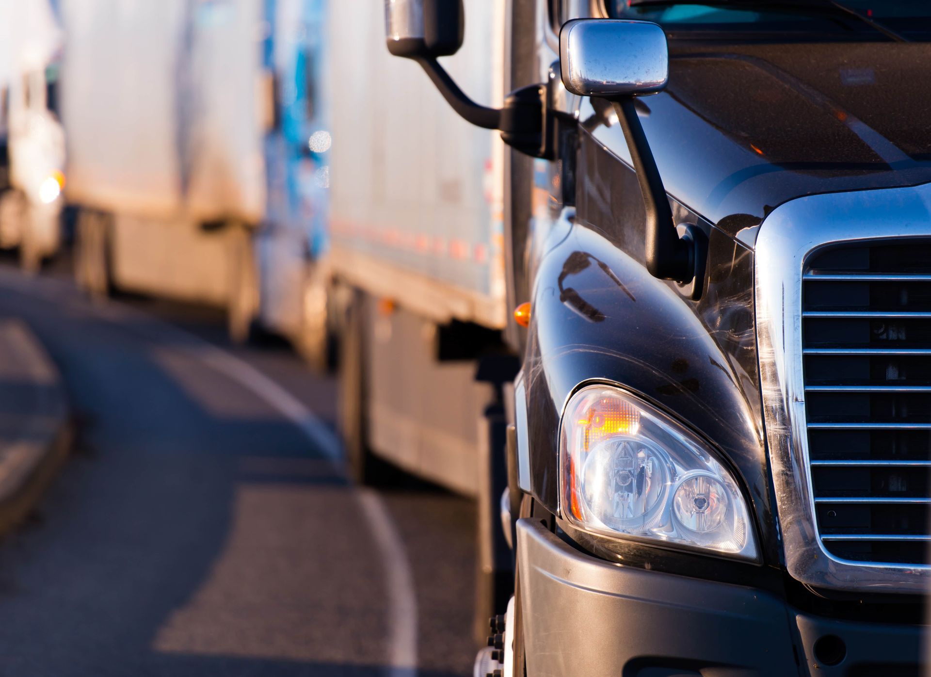 A row of semi trucks are driving down a highway.