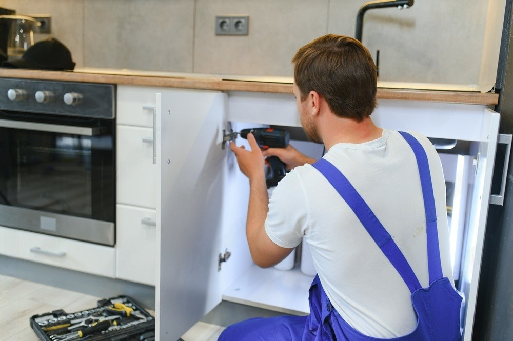 Skilled worker meticulously assembling kitchen furniture with precision and expertise.