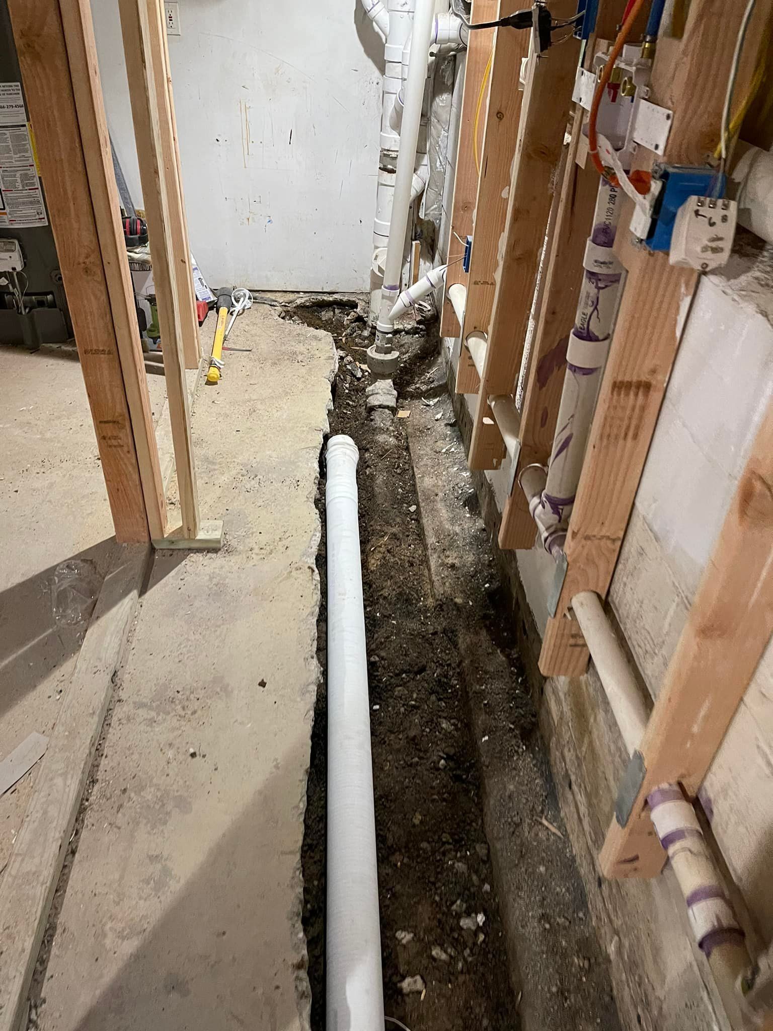A white pipe is being installed in a basement.