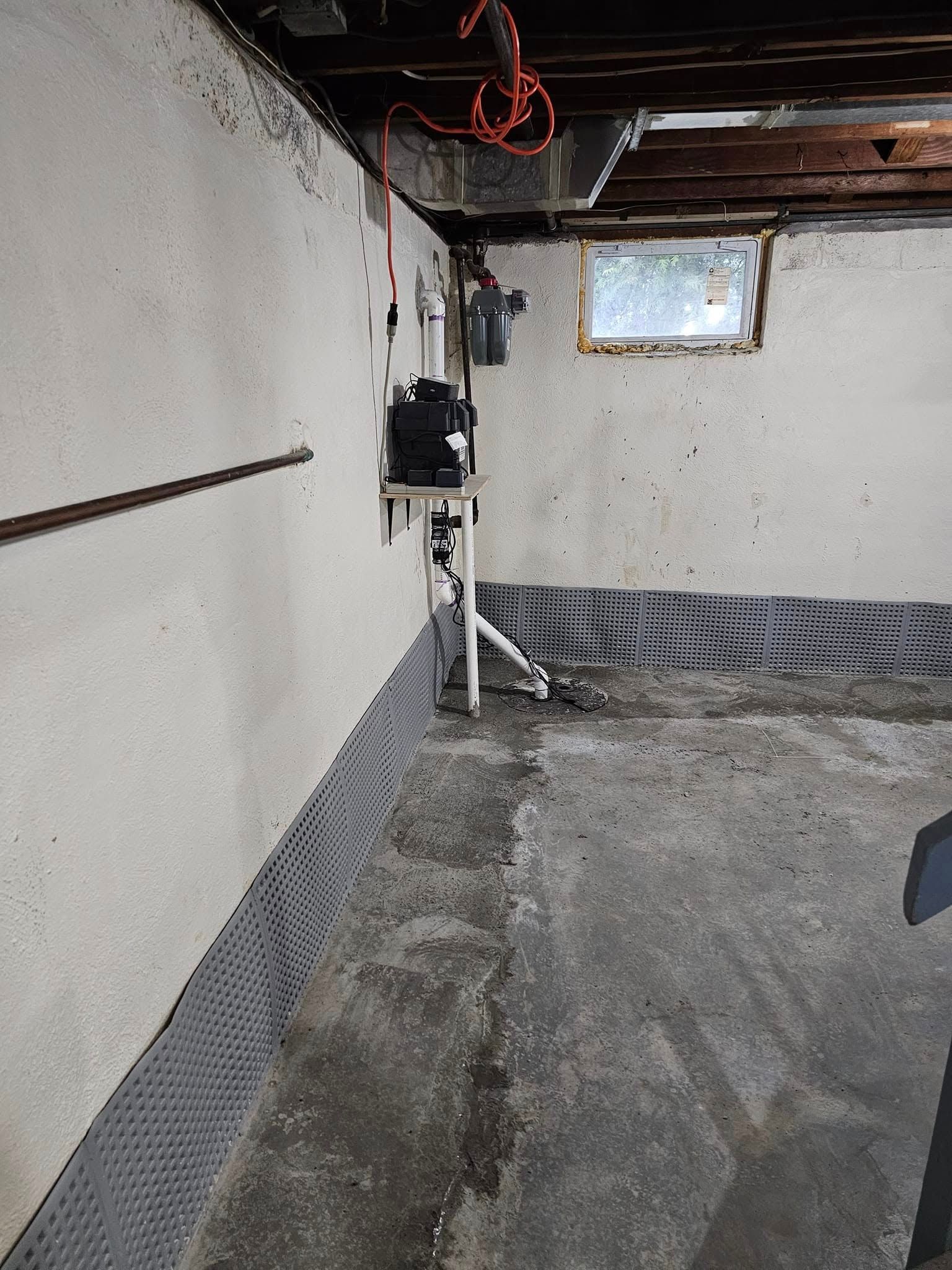 A dirty basement with a concrete floor and a window.