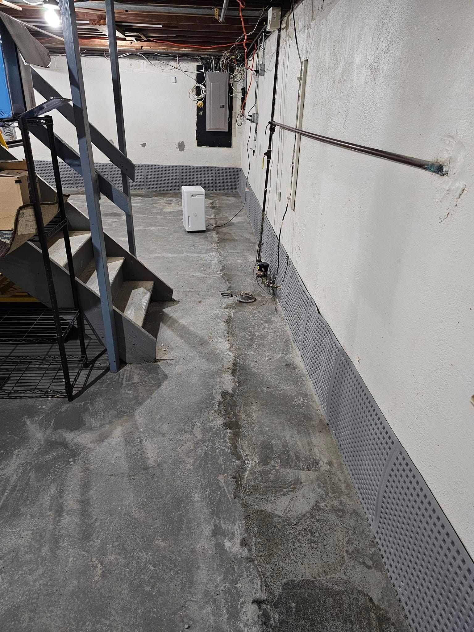 A basement with stairs and a white box on the floor.