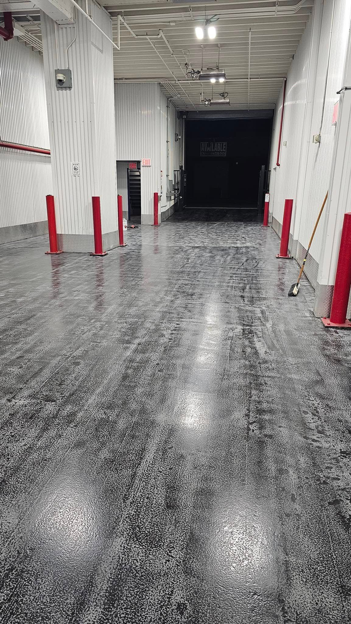 A long hallway with a black and white floor and red poles.