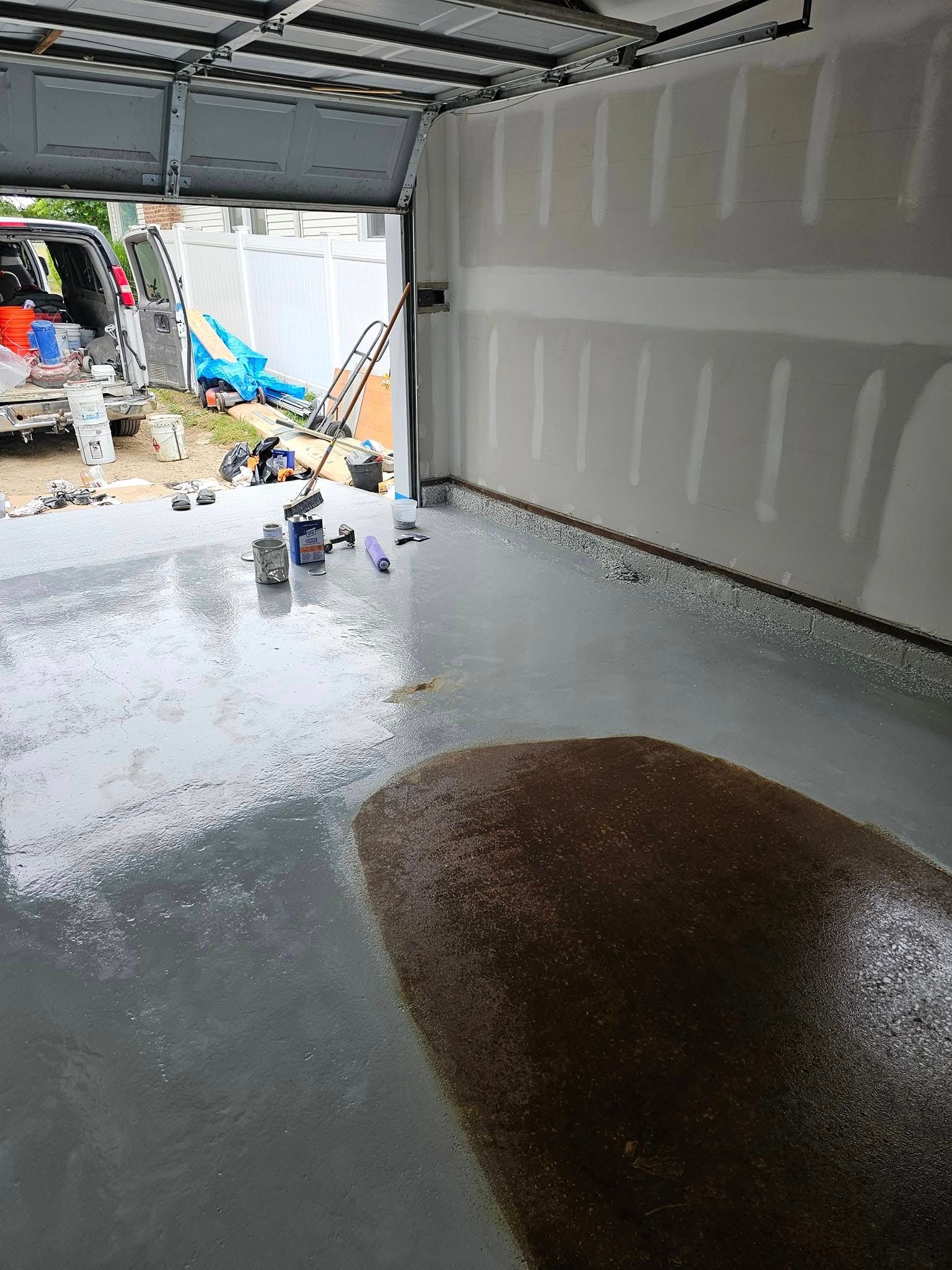 A garage with a concrete floor and a car parked in the background.