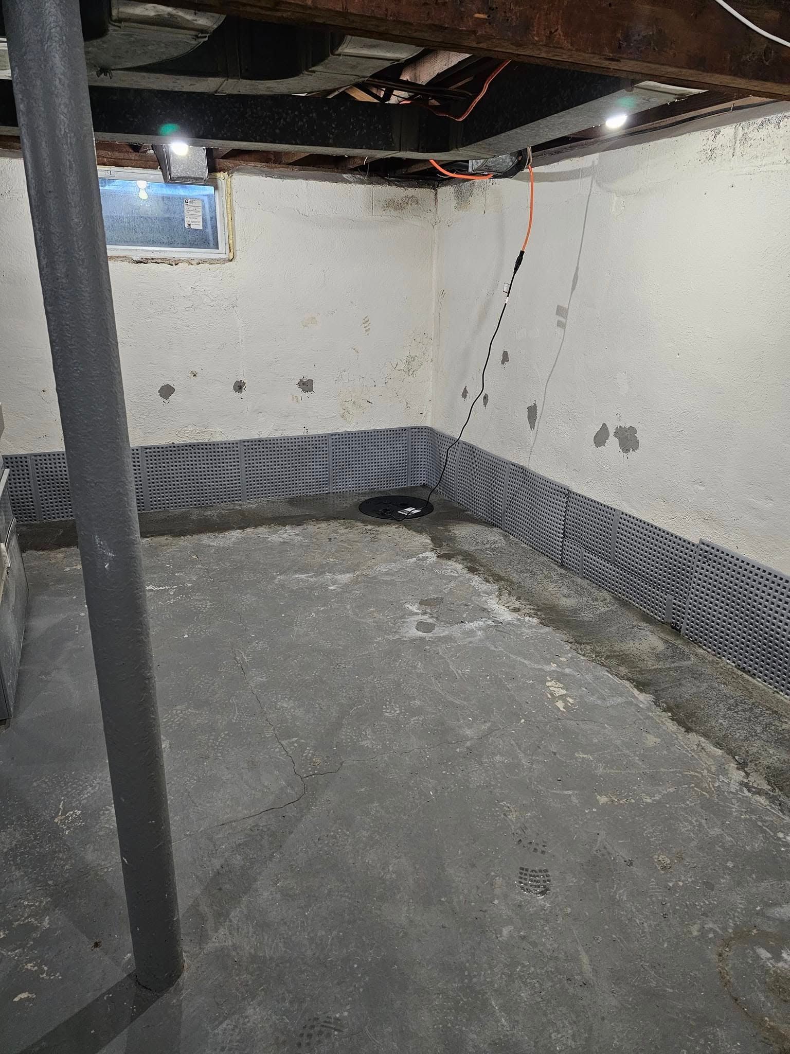 An empty basement with a window and a concrete floor.