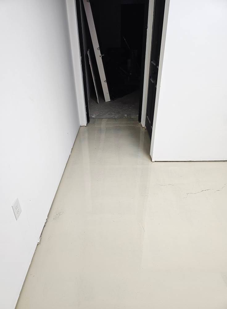 A hallway with a white floor and a black door.
