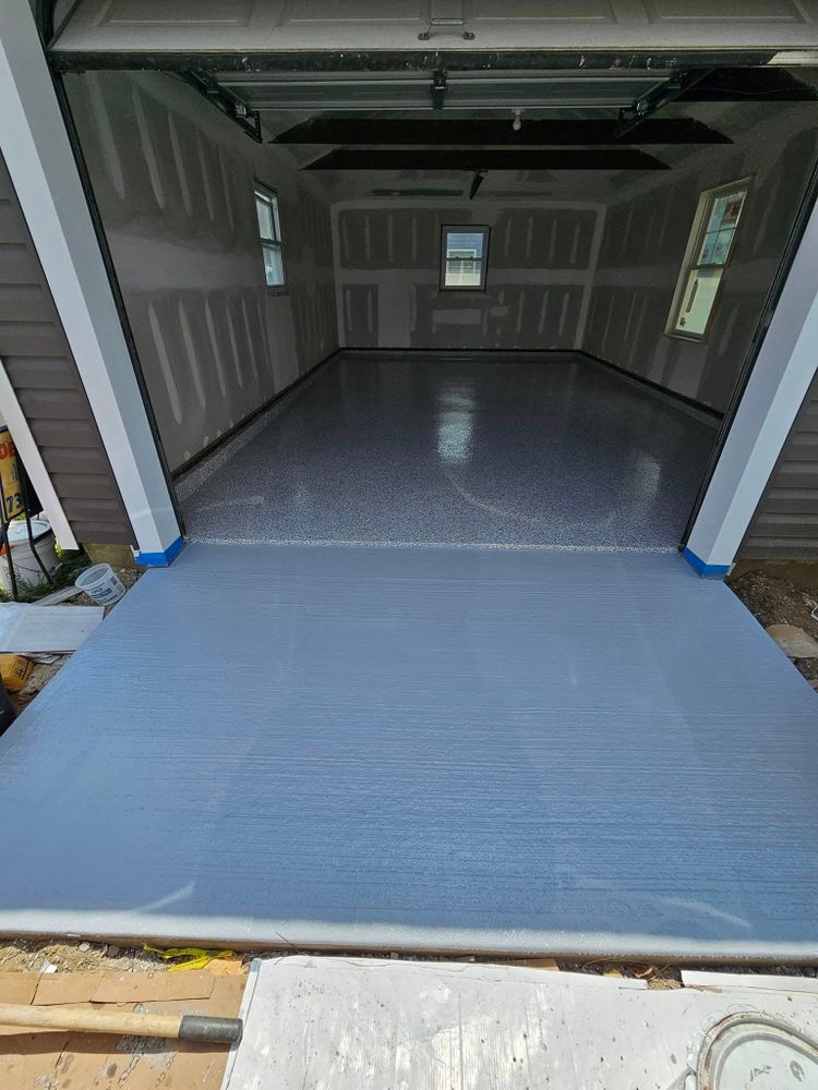 A garage with a gray floor and a garage door open.