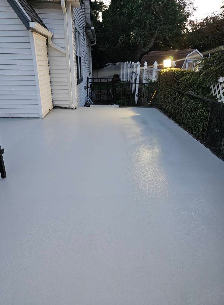 A white deck with a white fence in front of a white house.