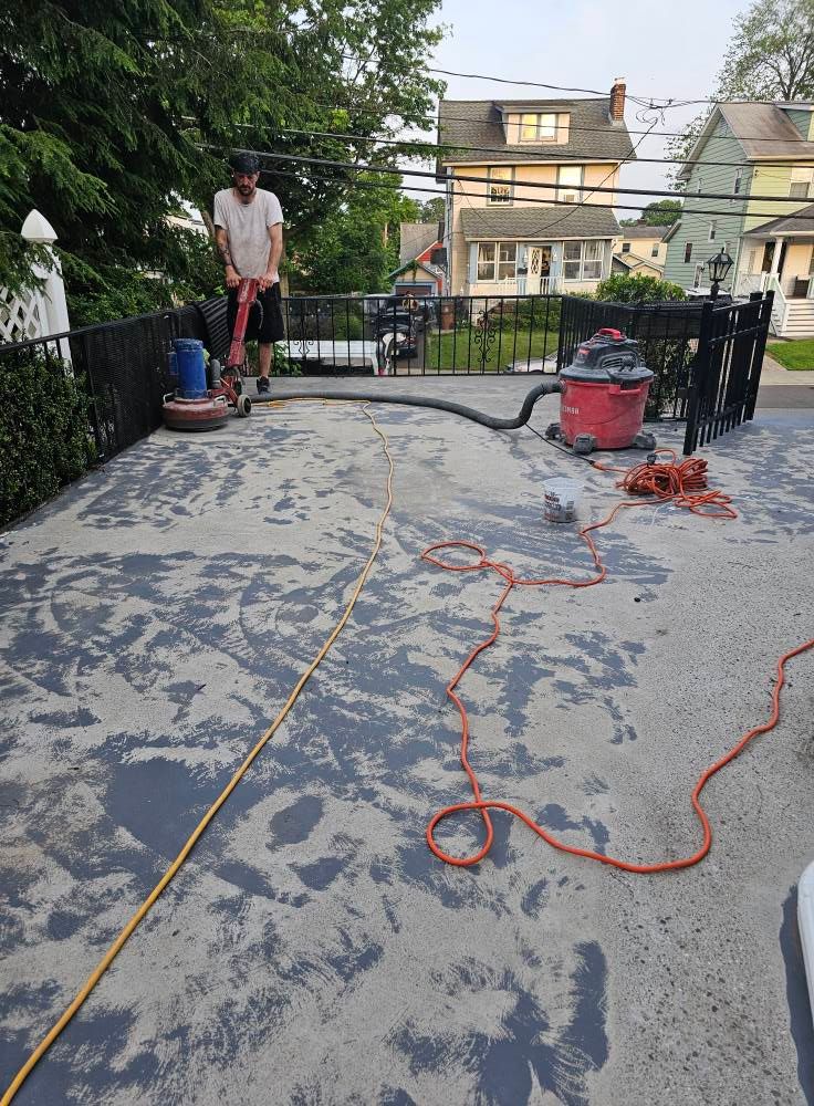 A man is using a vacuum cleaner to clean a concrete driveway.