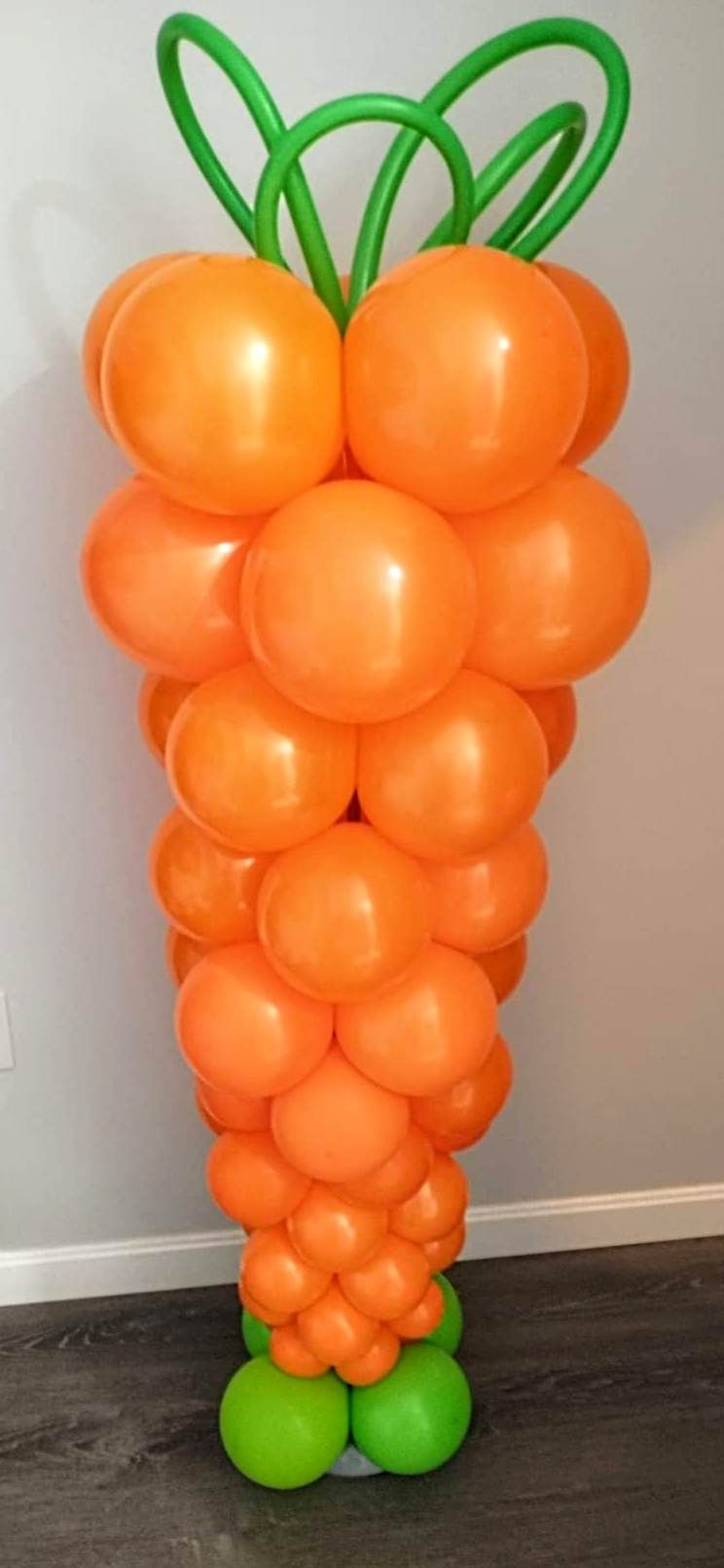 A bunch of orange balloons are stacked on top of each other to look like carrots.