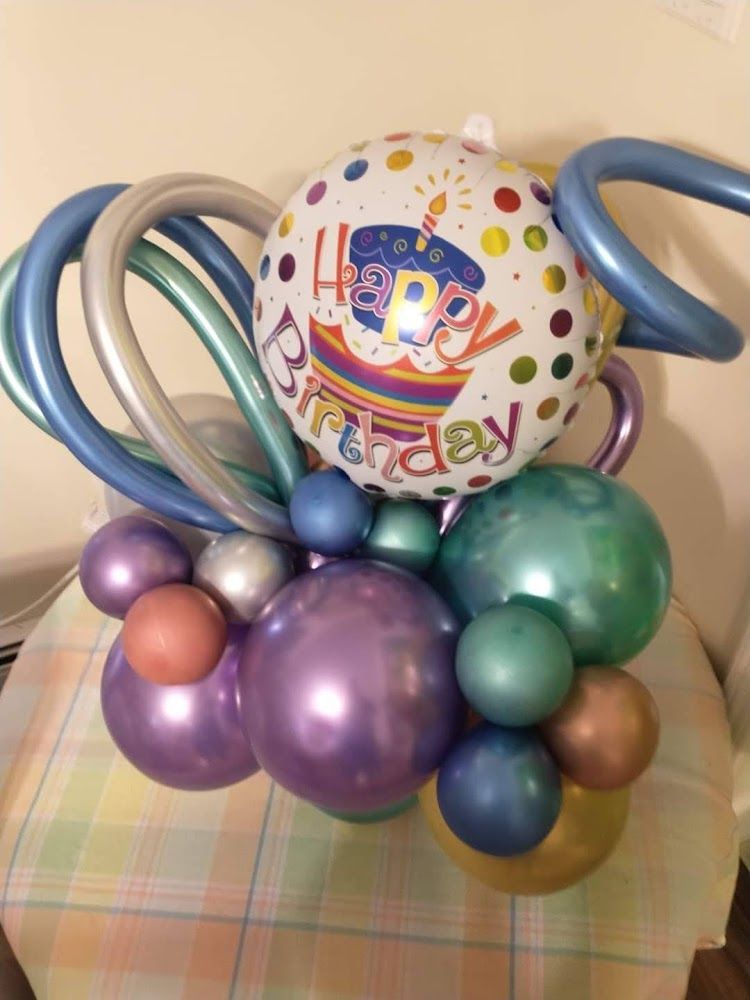 A happy birthday balloon is surrounded by other balloons