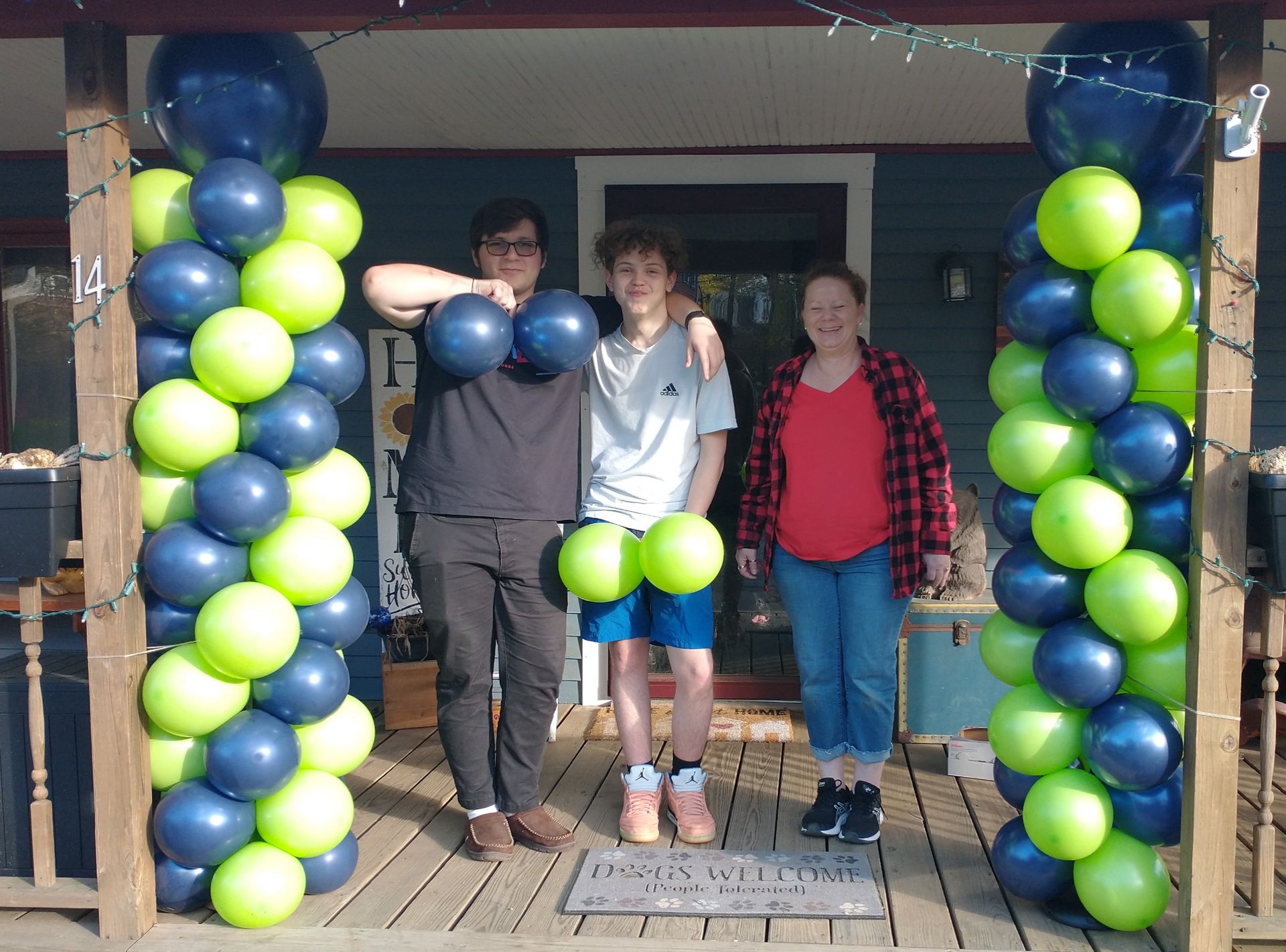 A group of people standing on a porch with balloons.