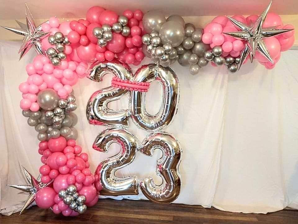 A pink and silver balloon arch with the number 20 and 23 balloons.