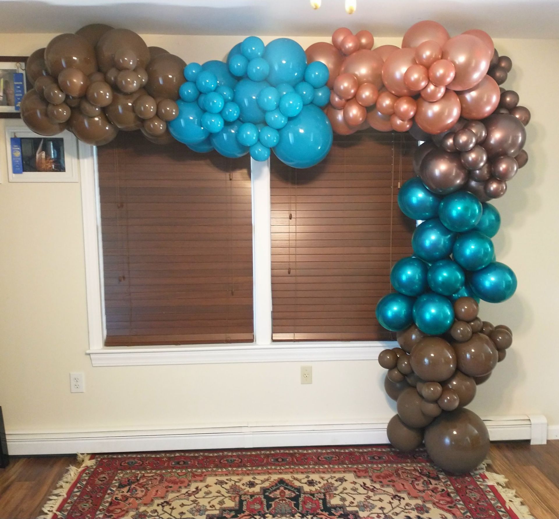 A bunch of balloons are hanging on a wall in front of a window