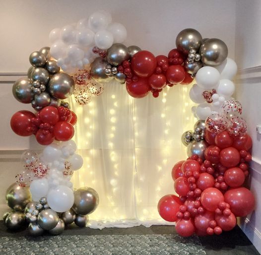 A room filled with red , white and silver balloons and lights.