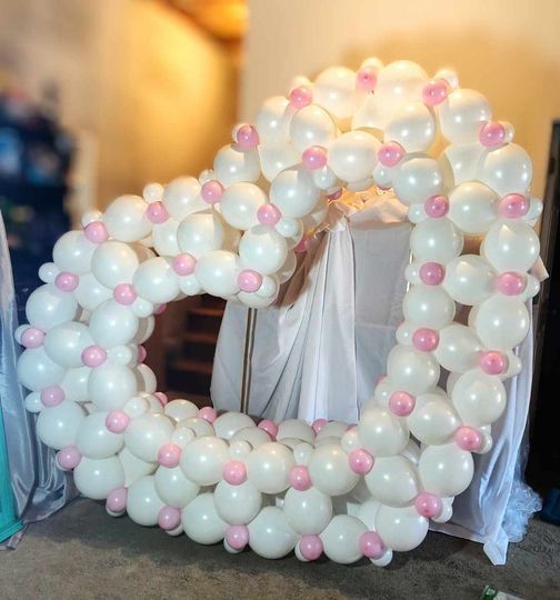 A heart made of white balloons with pink beads