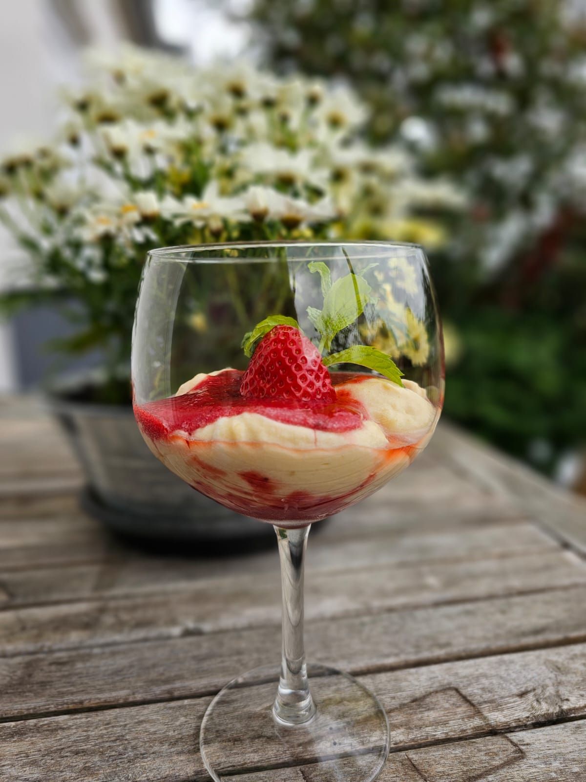 Ein Glas Wein mit einer Erdbeere darauf auf einem Holztisch.