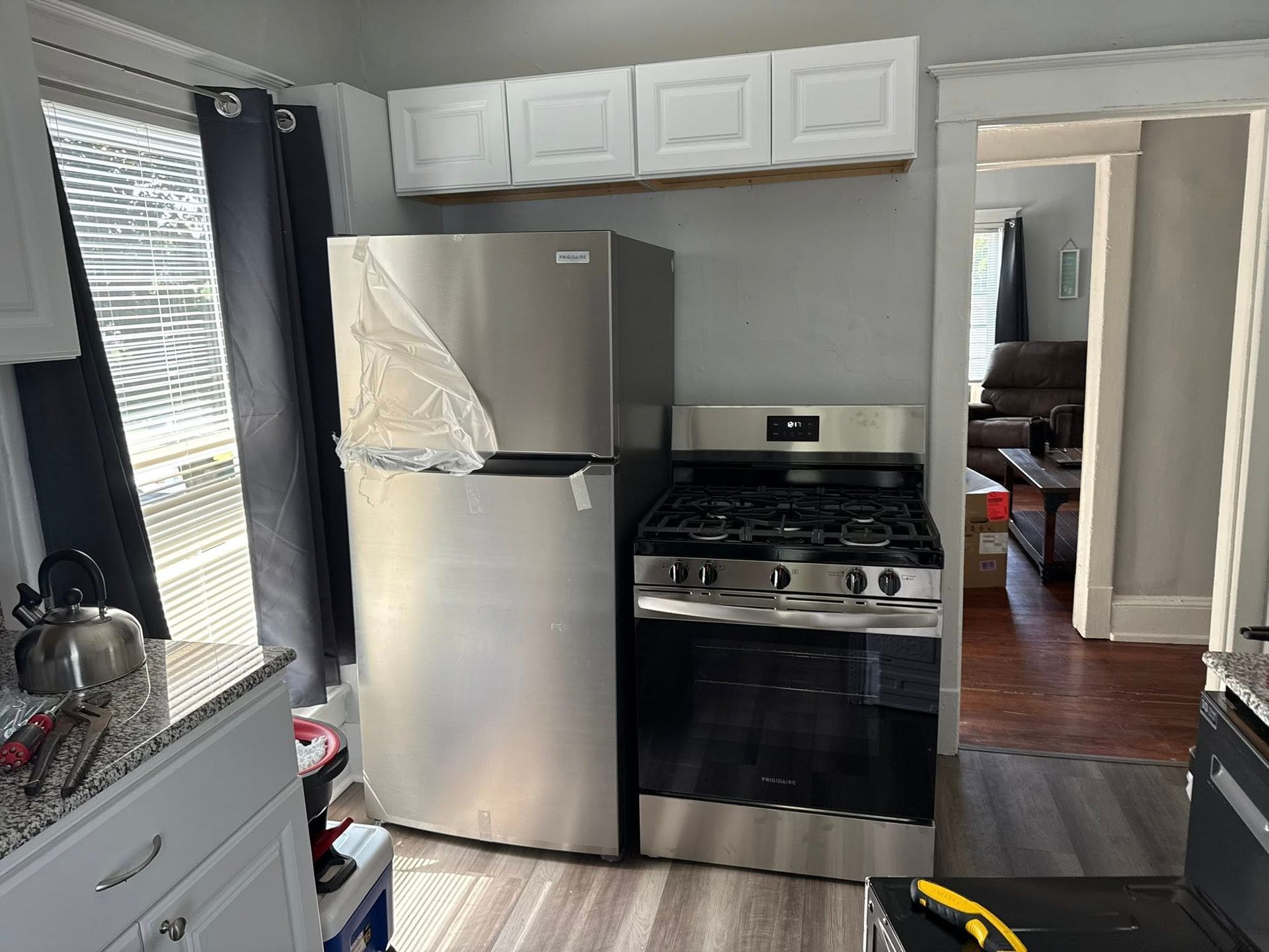 Kitchen with a stainless steel refrigerator and gas stove, white cabinets, and a doorway to another room.