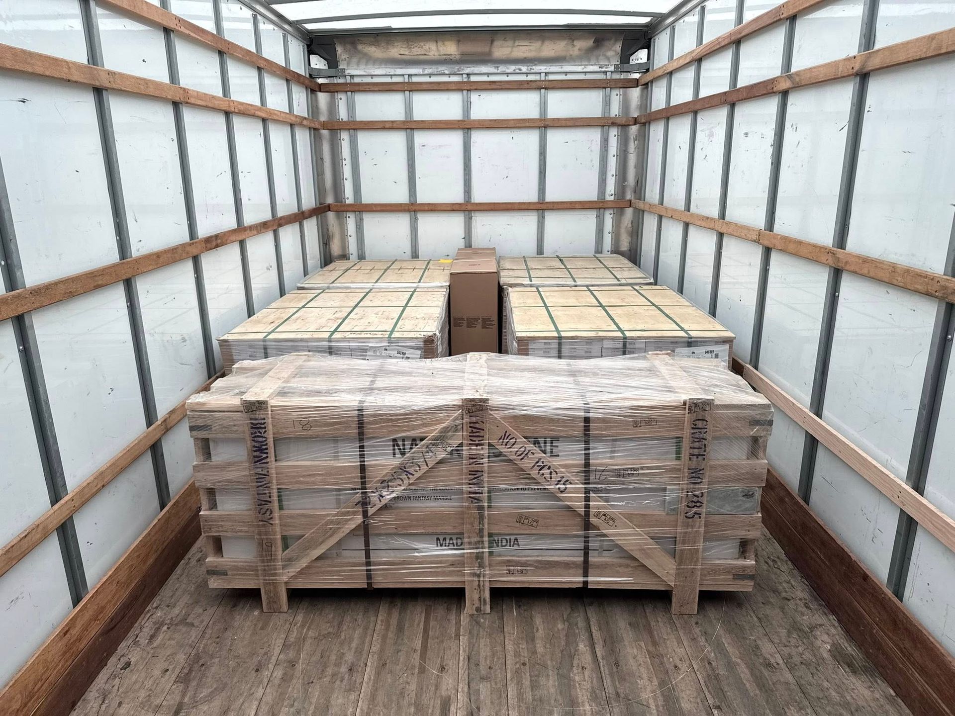 Interior of a cargo truck loaded with multiple wooden crates and boxes, secured for transport.