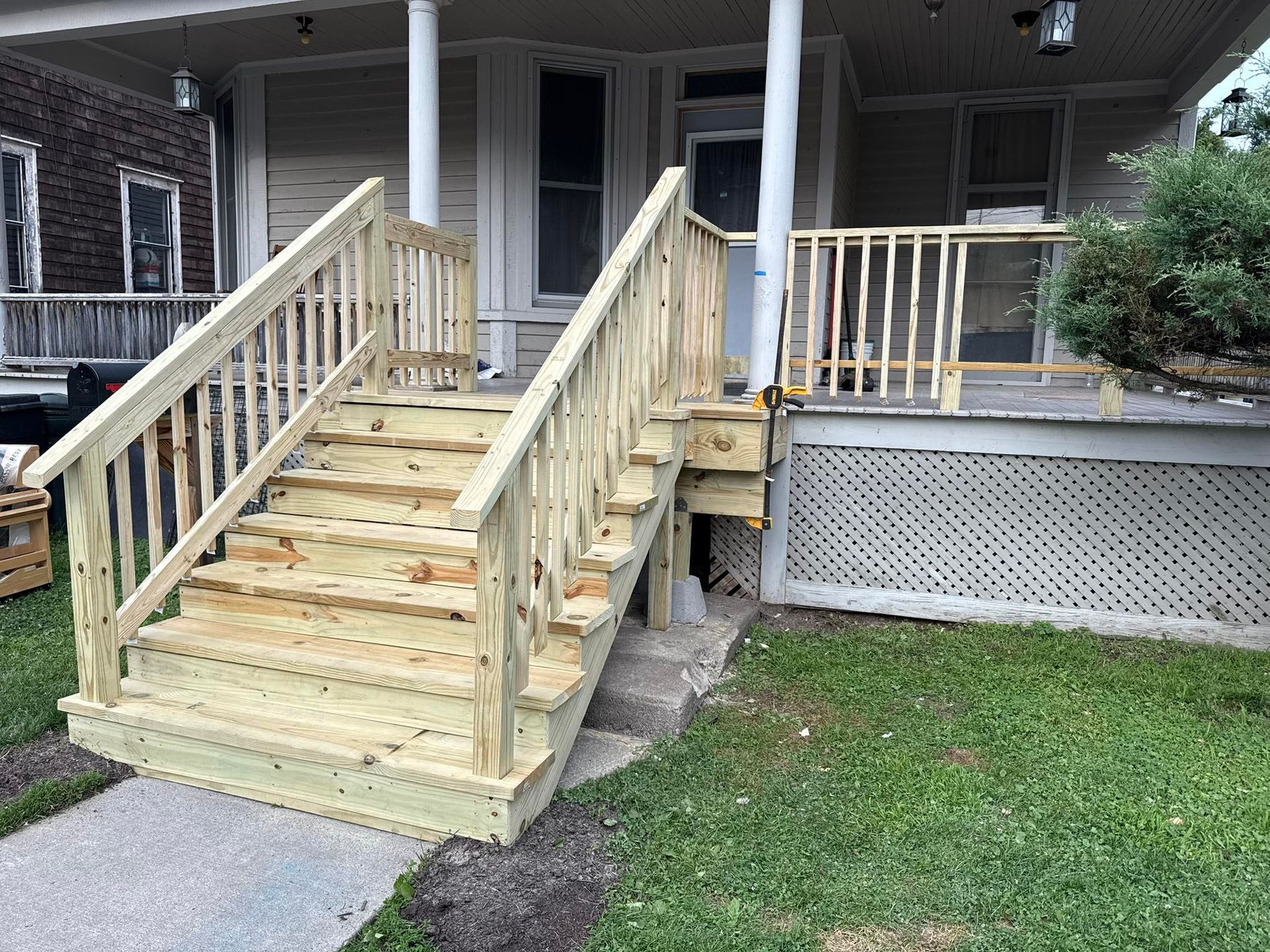 Newly constructed wooden front porch steps leading to a house with a porch.