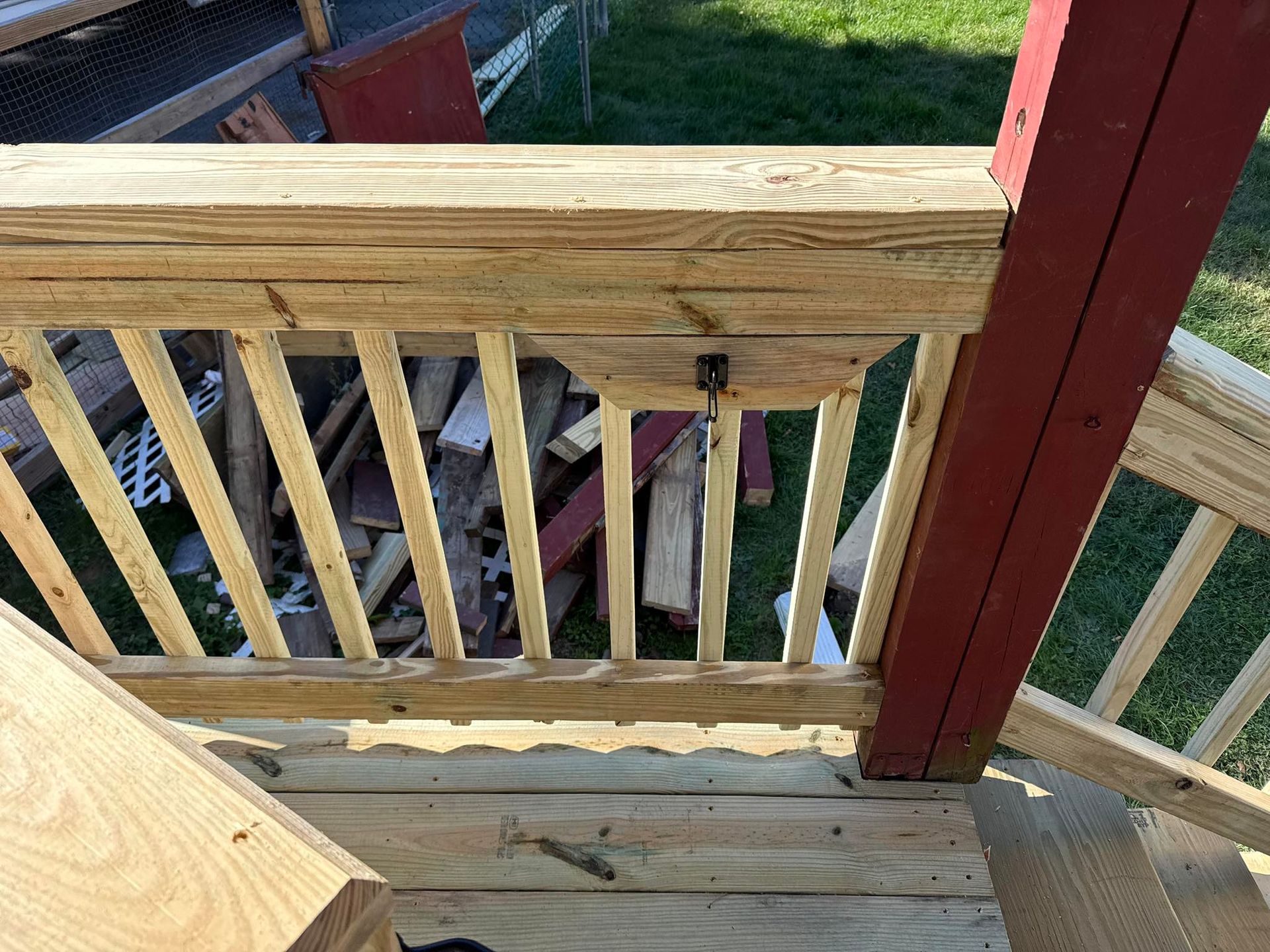 Wooden deck with railing, a red post, and wood pile in the background.