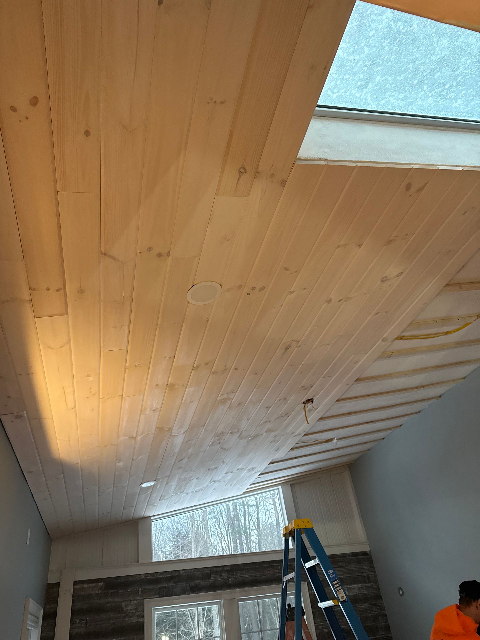 Wood ceiling installation with skylight and ladder.