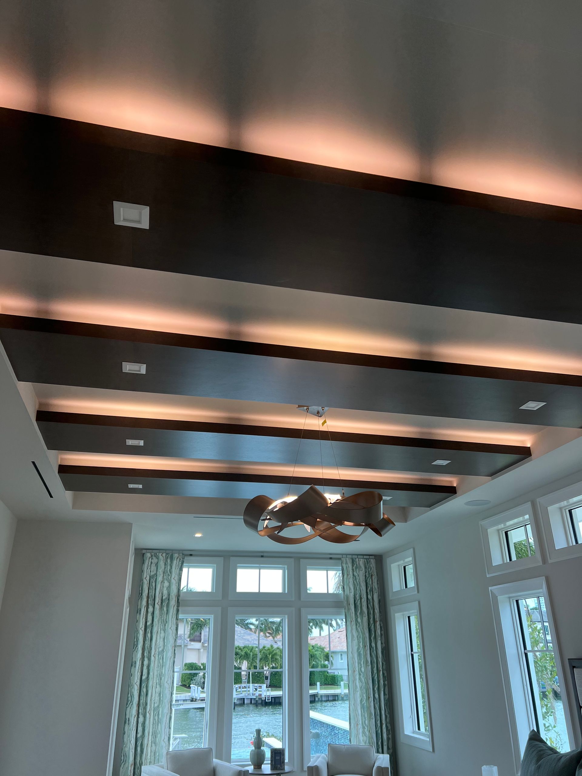 Interior with dark wood beams and ambient lighting over a window with a view of water.