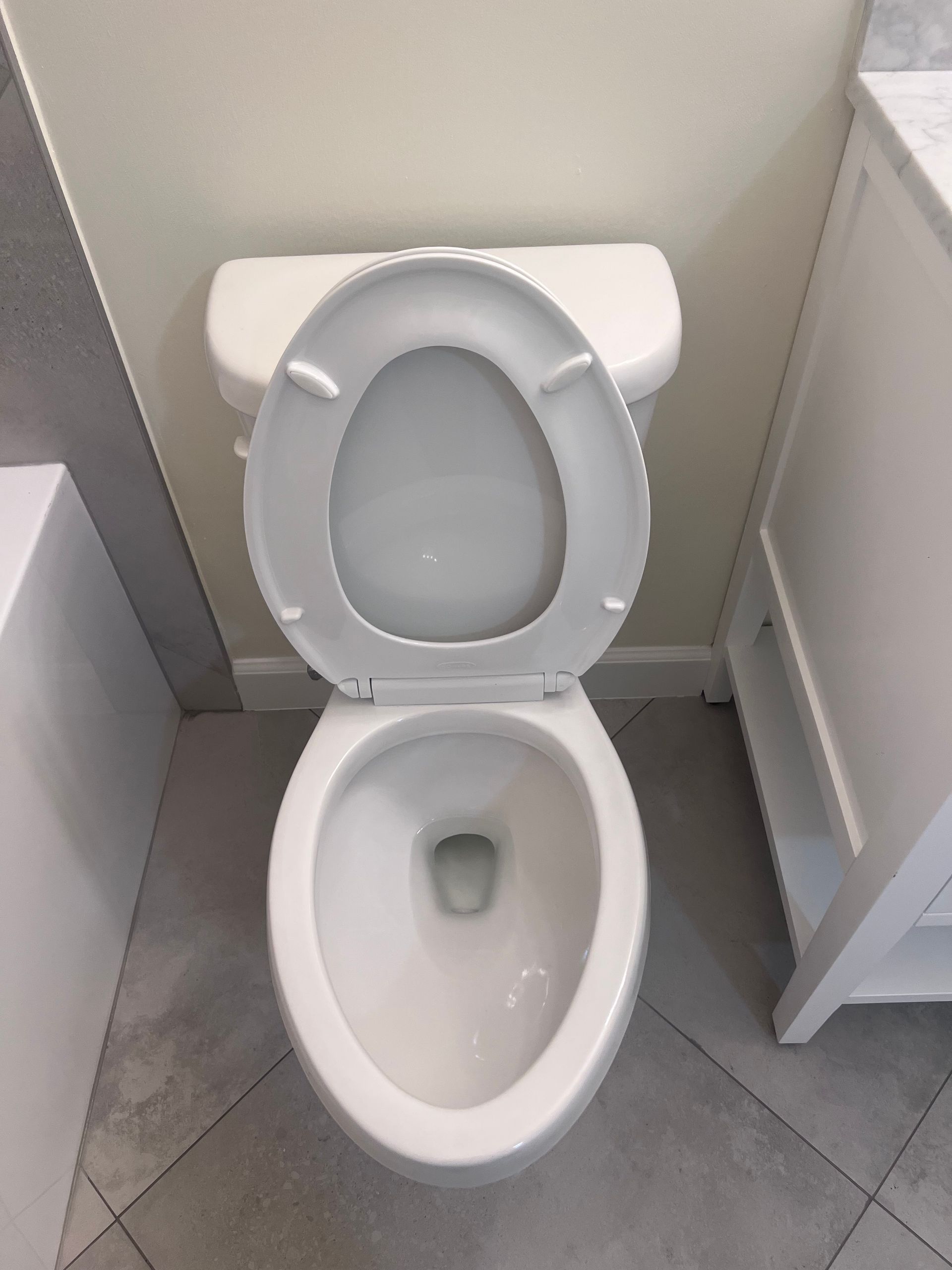 White toilet with the seat up, in a bathroom with tile floor.