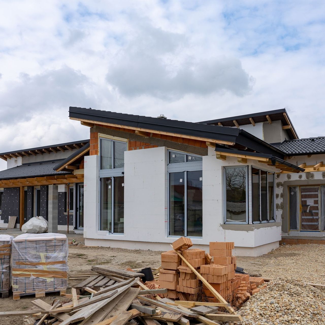 A house under construction with a pile of bricks in front of it