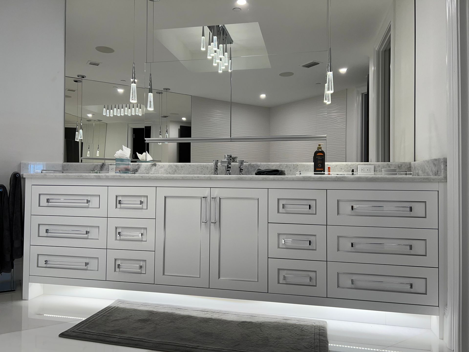 White bathroom vanity with gray countertop, mirror, and pendant lights.
