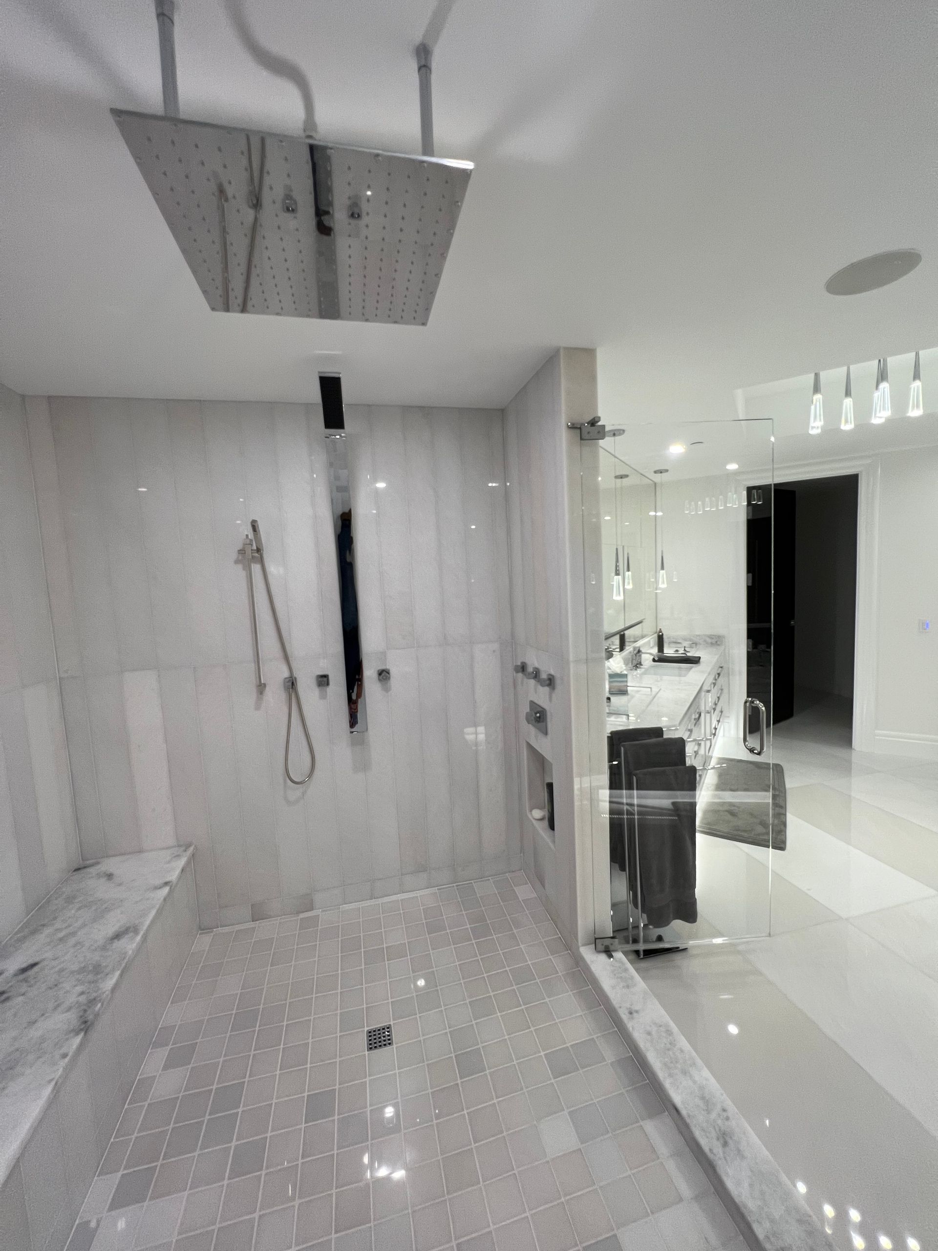 Spacious modern bathroom with a large shower, marble tiles, and a bench.