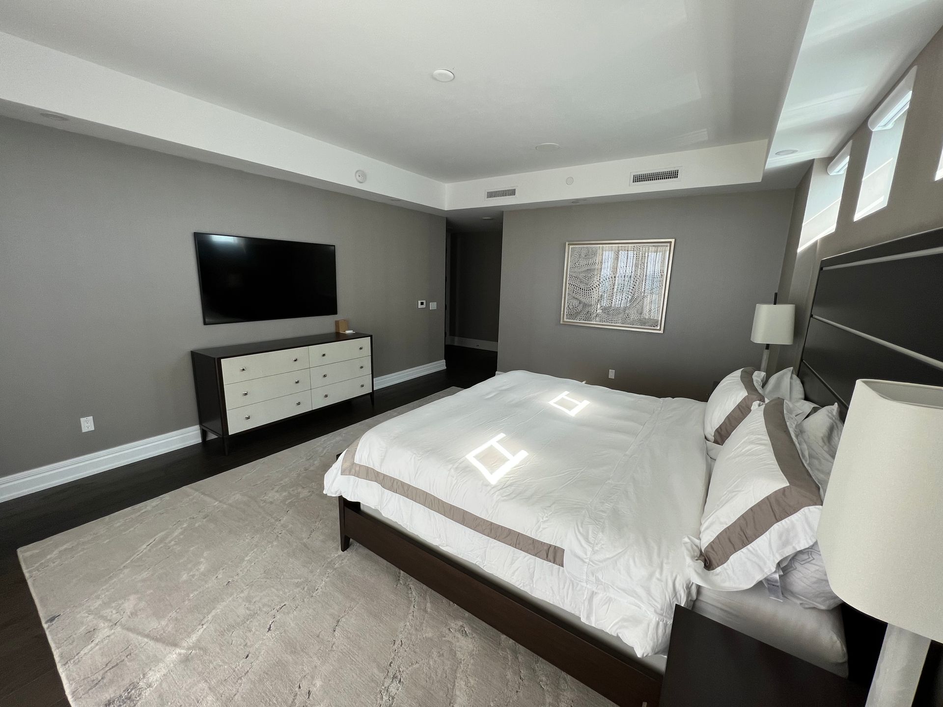 Bedroom with gray walls, dark wood furniture, and a large bed with decorative pillows.