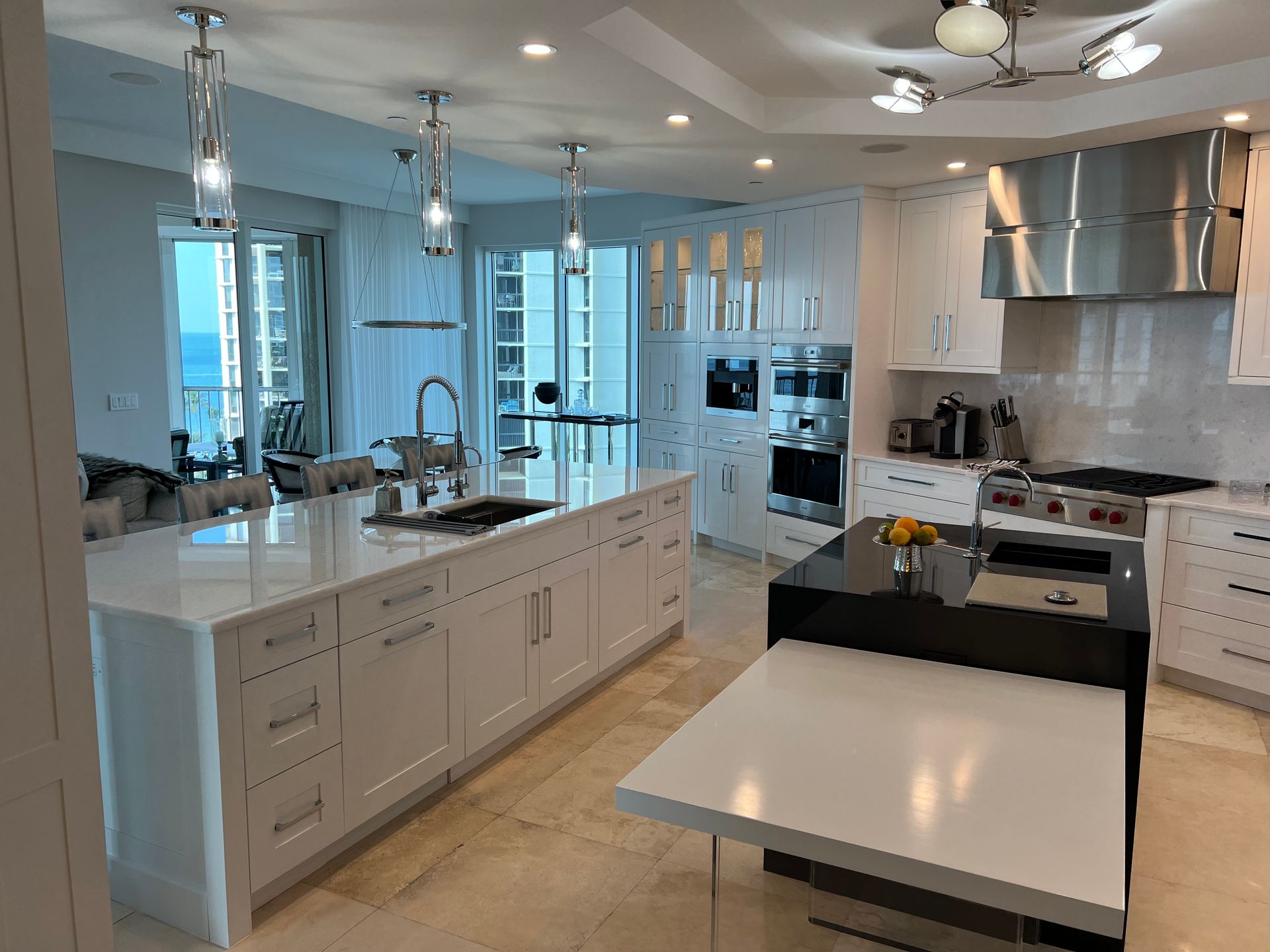 Bright, modern kitchen with white cabinetry, a large island, and a black island with a waterfall countertop.