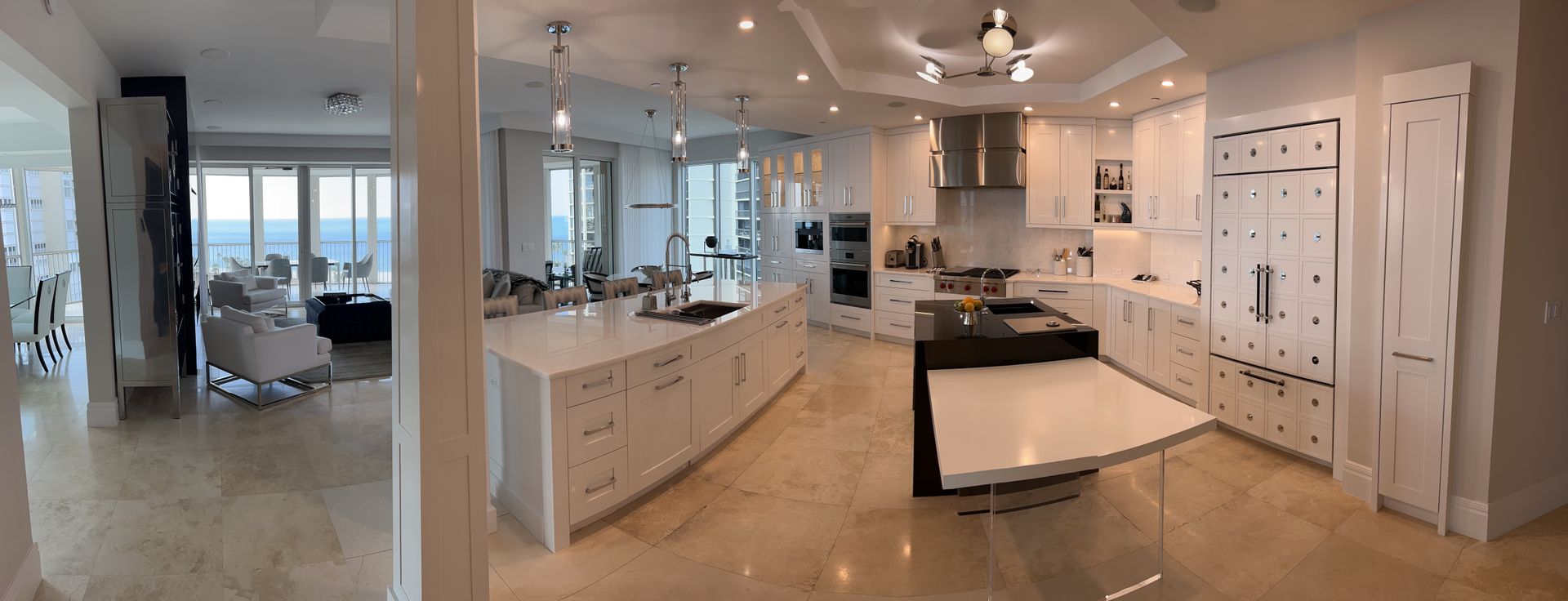 Upscale kitchen with a large island, white cabinetry, and open concept living area.