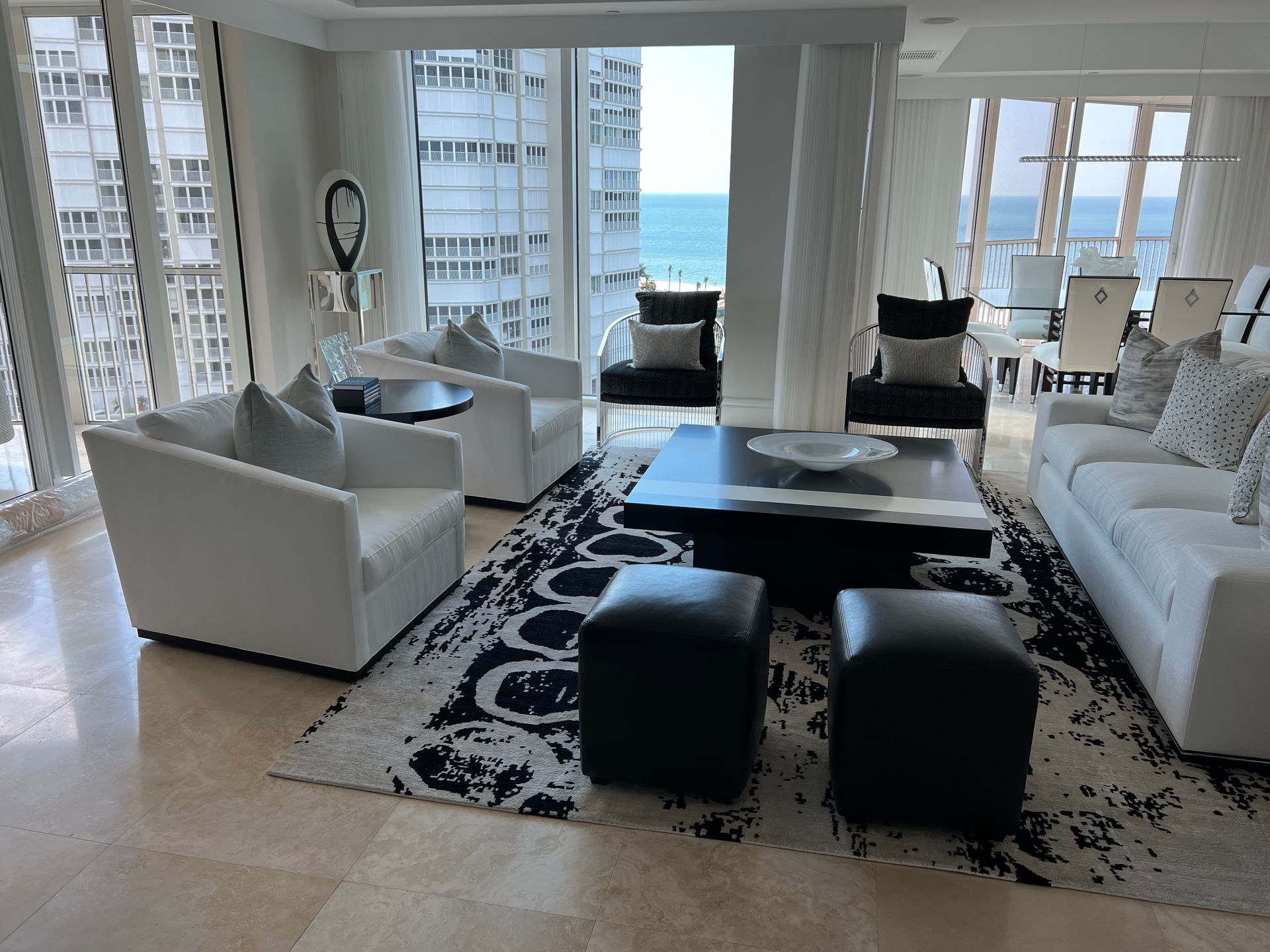 Bright living room with white and black furniture, ocean view.
