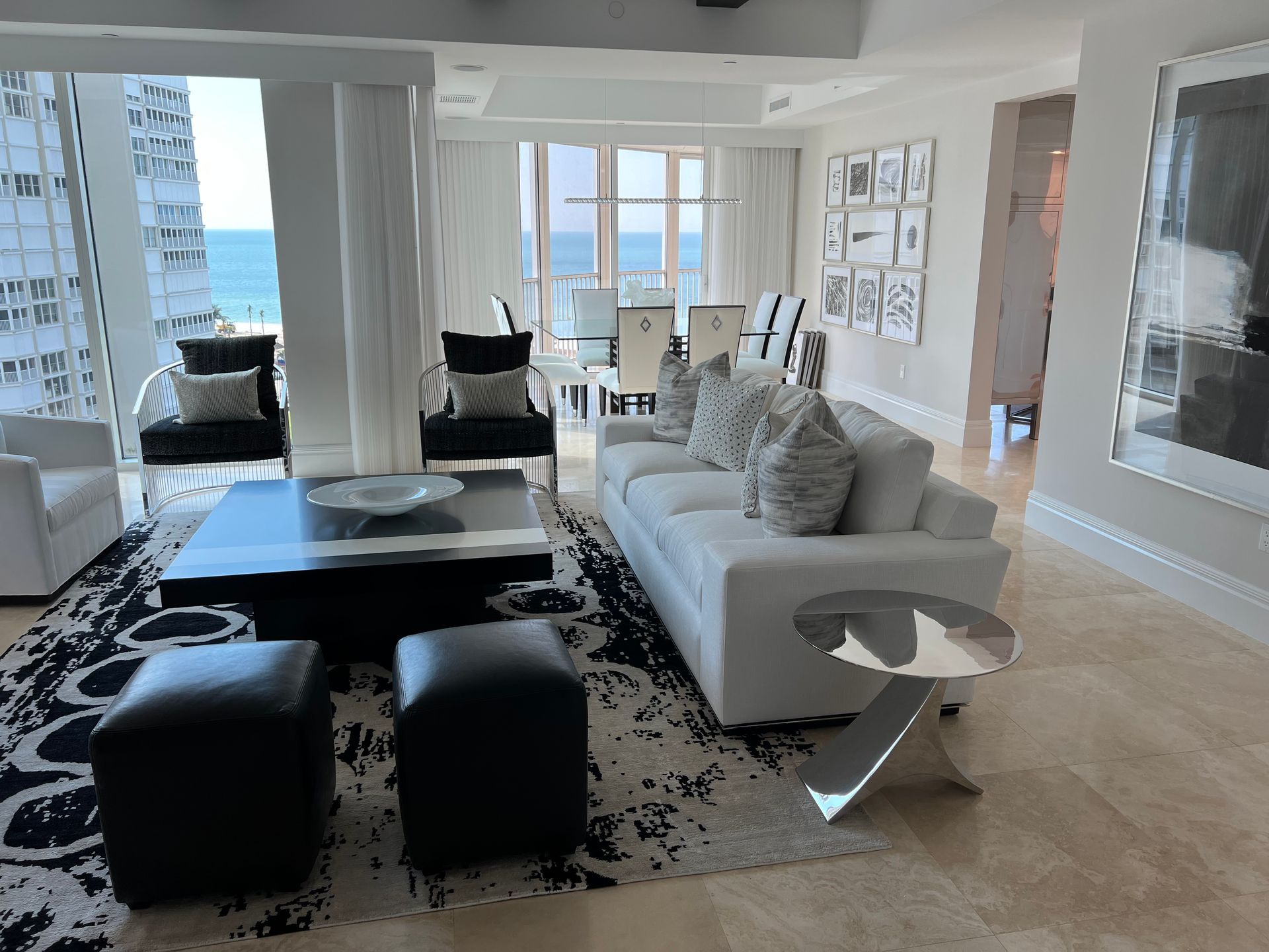 Luxurious modern living room with ocean view, white and black furniture, and a patterned rug.