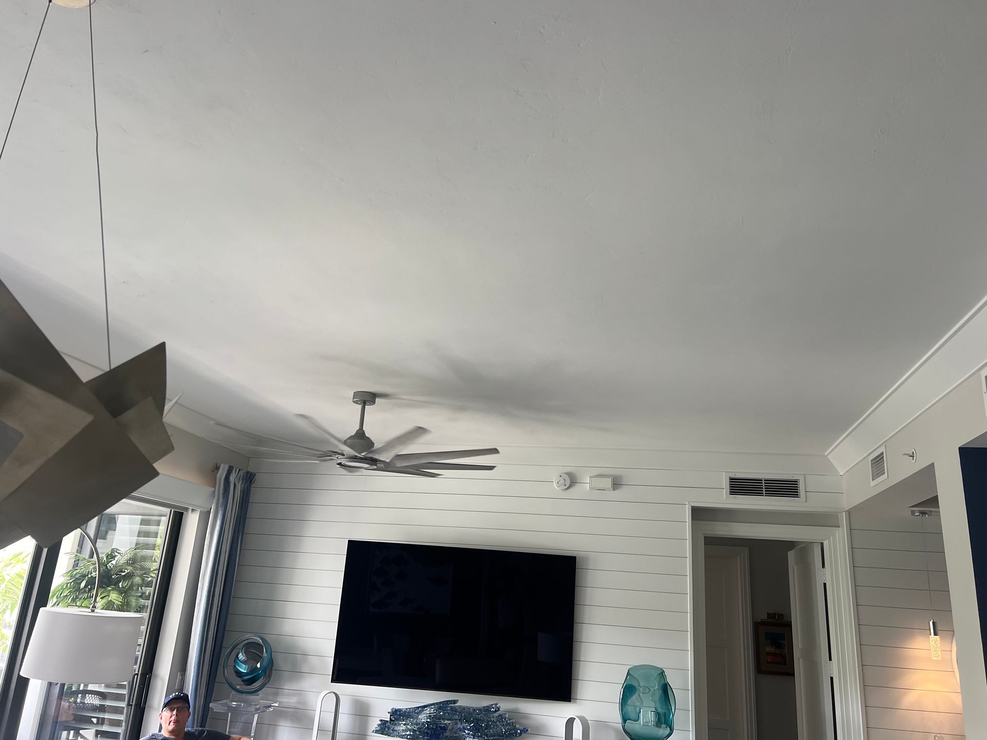Living room with TV, ceiling fan, and decorative wall.