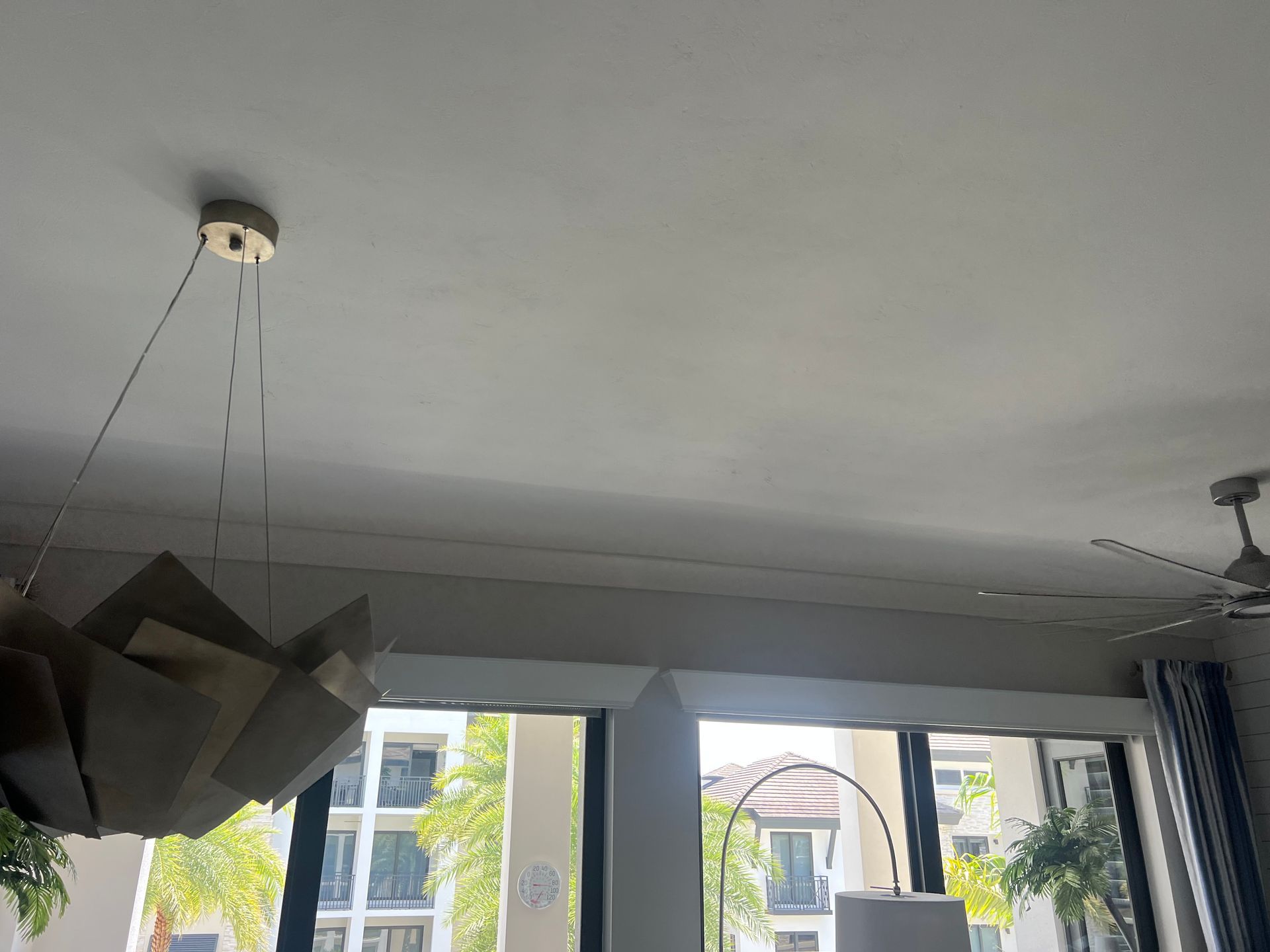 A modern ceiling with a light fixture, window, and a ceiling fan.