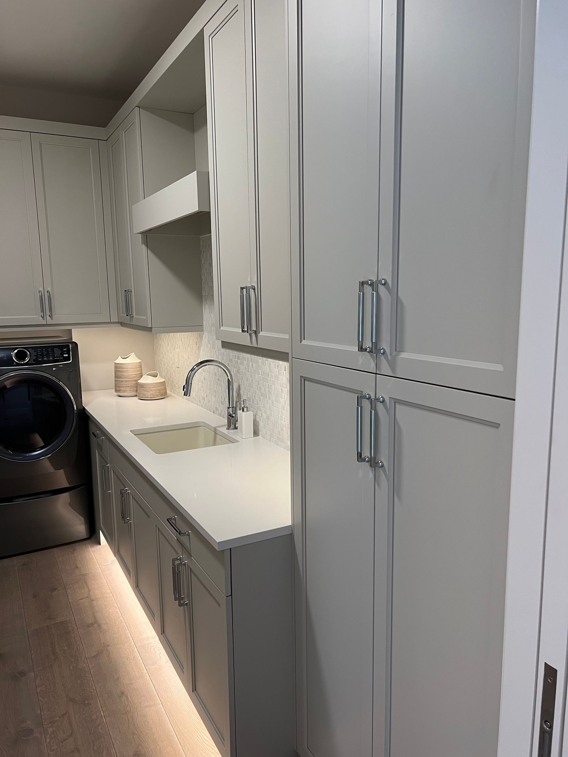 Laundry room with light gray cabinets, countertop, sink, and washer and dryer.