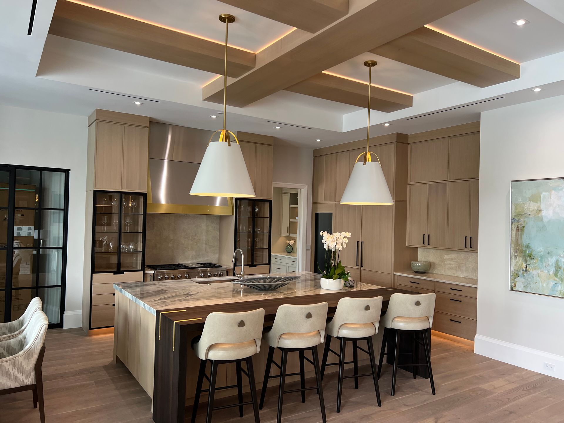 Upscale kitchen with island, pendant lights, wood cabinets, and bar stools.