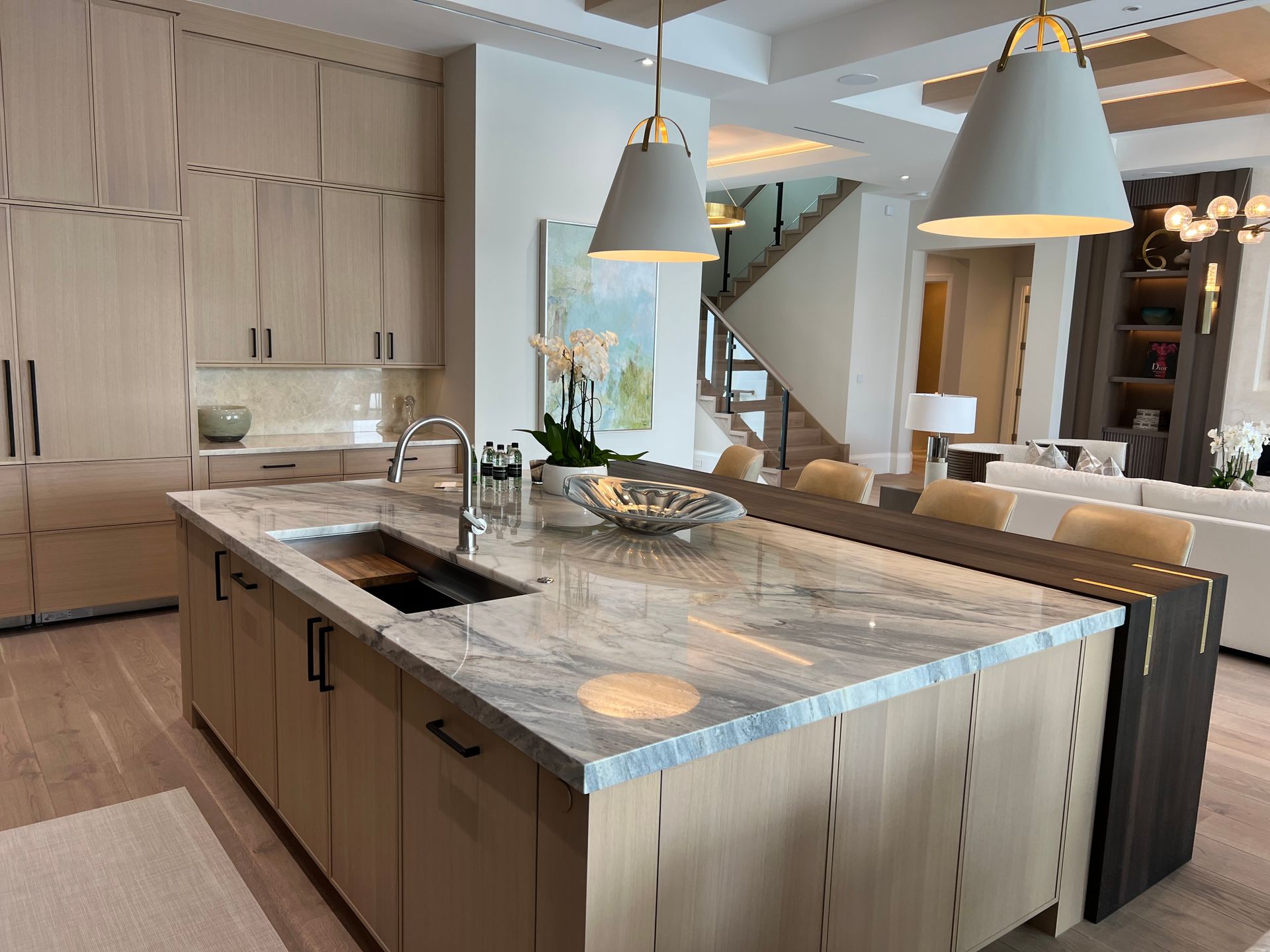 Modern kitchen with light wood cabinets, gray island countertop, and pendant lights.