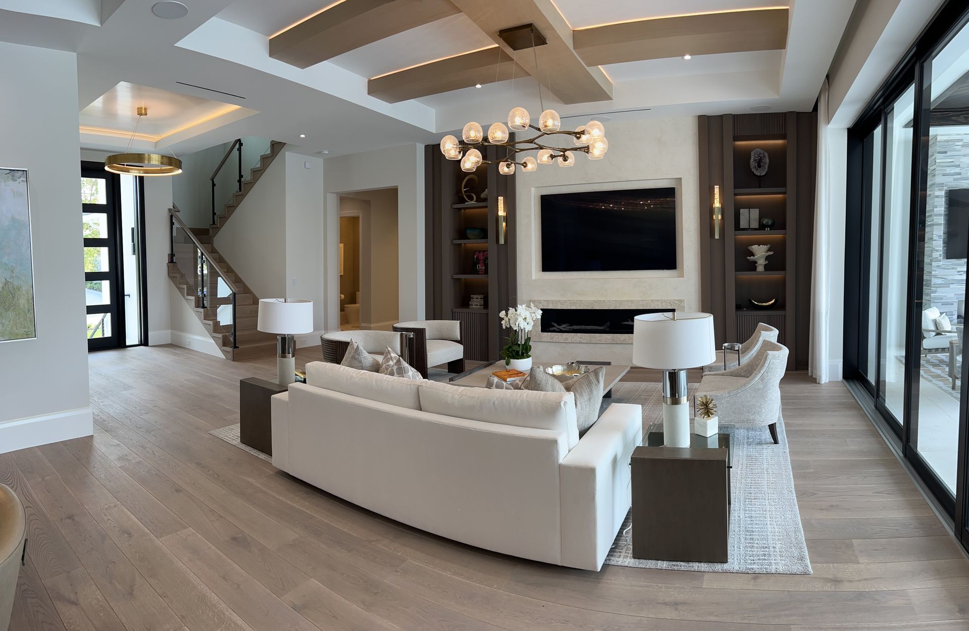 Luxurious living room with white sofa, TV, fireplace, and large windows.