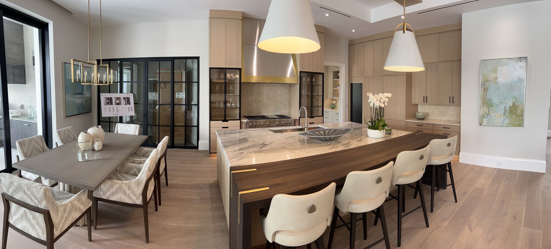 Spacious kitchen and dining area with a large island, bar stools, and a dining table. Neutral tones.