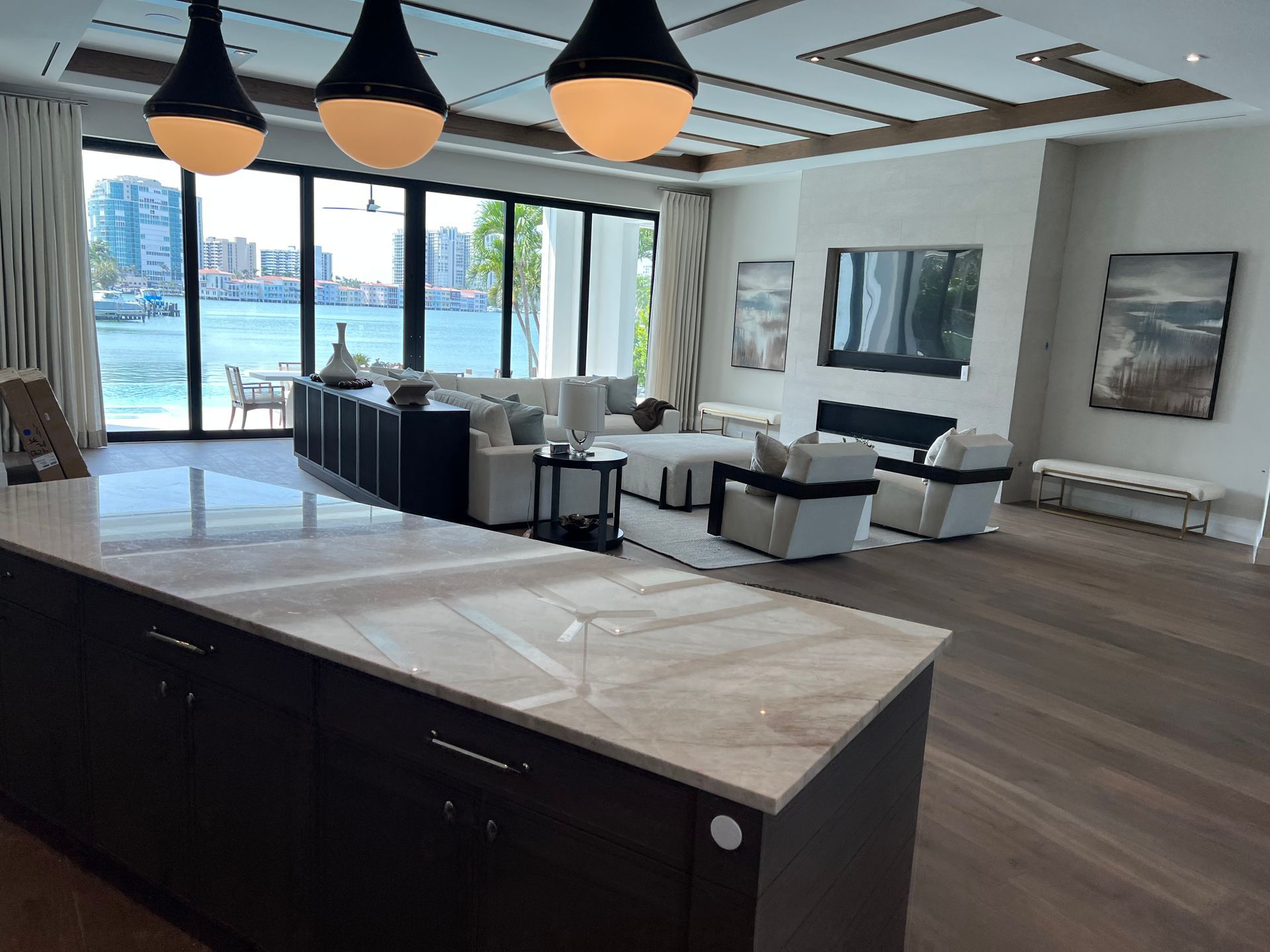Luxury living room with water view, neutral colors, dark cabinets, and modern furniture.