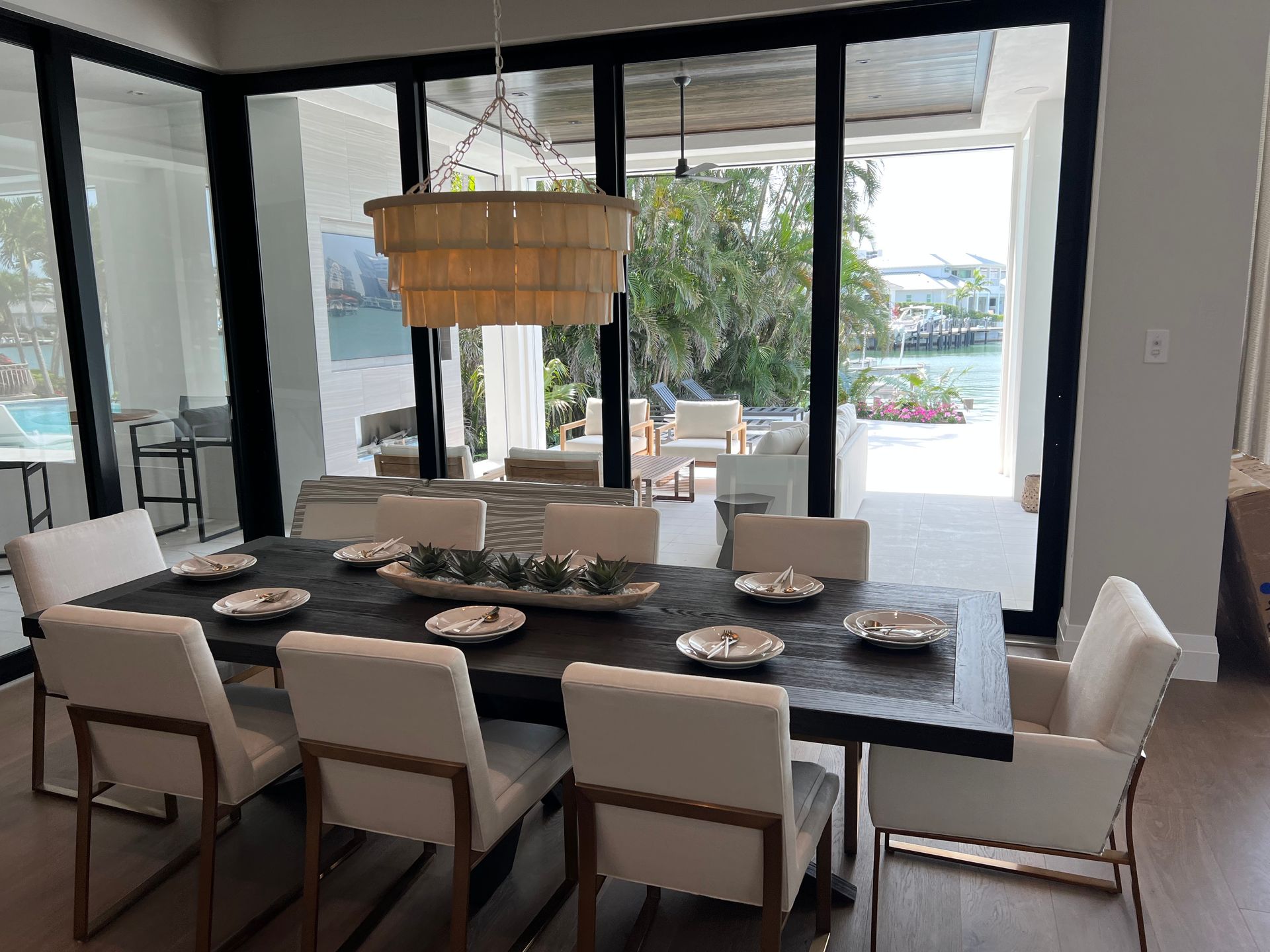 Dining room with dark table, white chairs, and outdoor view.