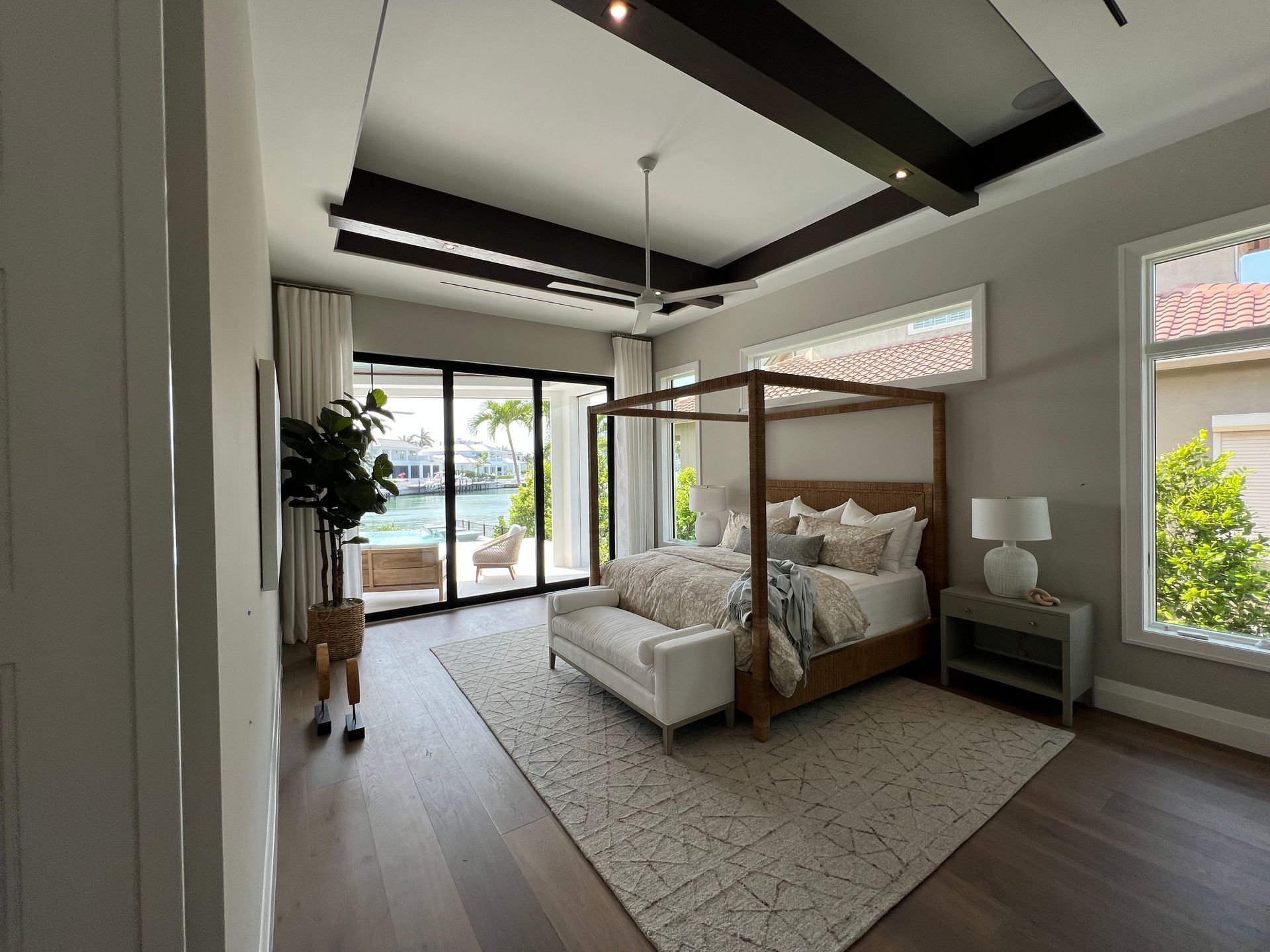 Bedroom with a canopy bed, sliding doors to a patio, and water view.
